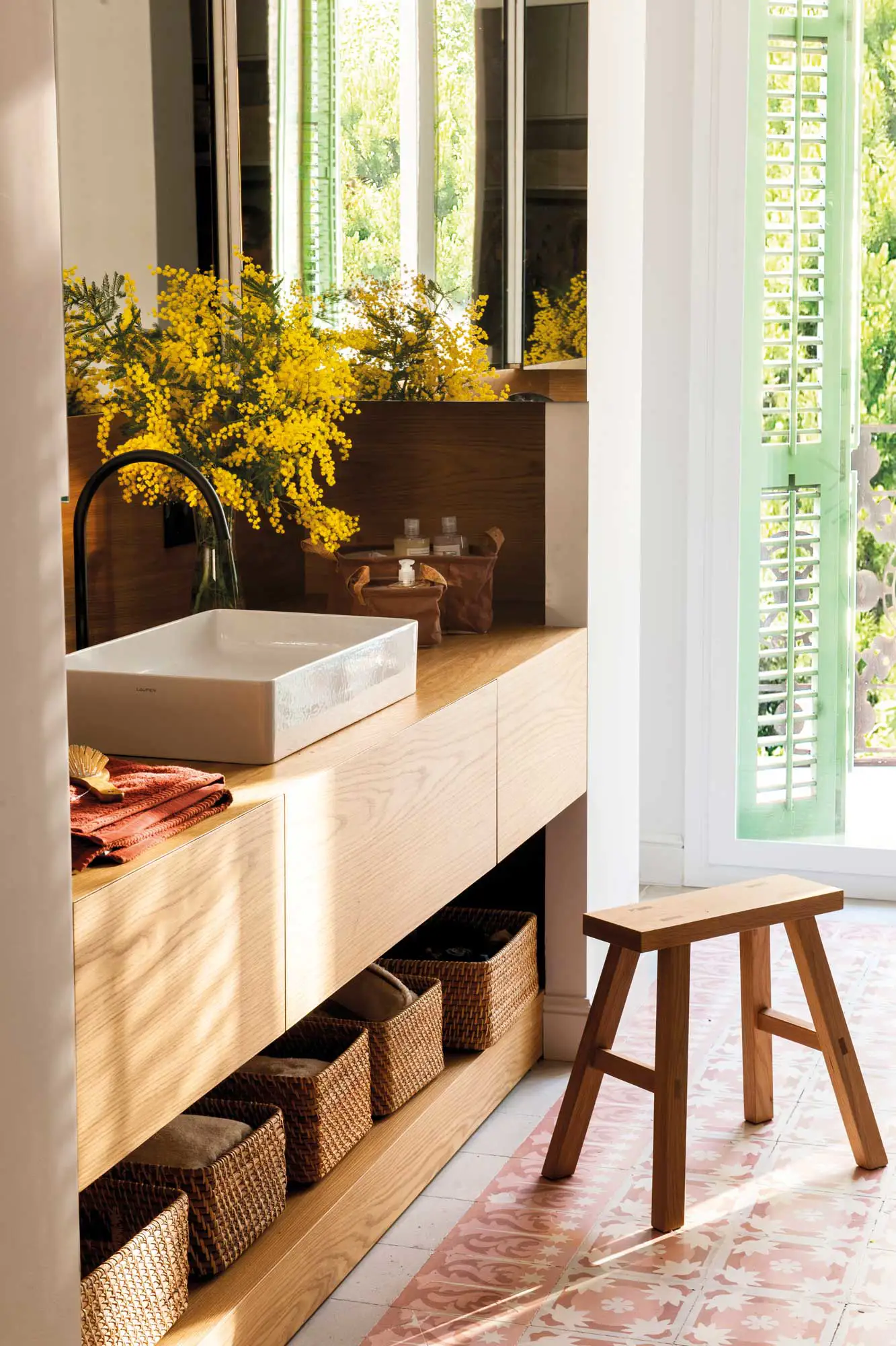 Baño moderno con mueble de madera y cestas de fibra.