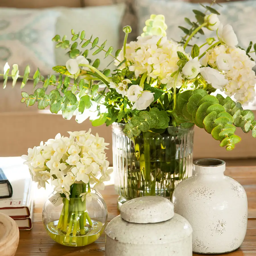 Jarrones de cerámica blanca y de cristal con flores blancas y verdes