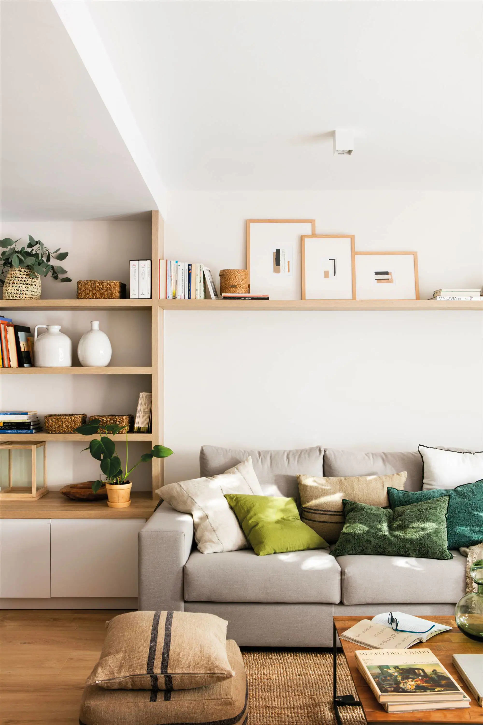 Salón con sofá gris, estantería y estante flotante con cuadros