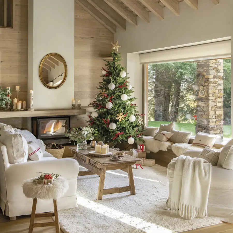 Salón rústico con vigas, sofás blancos, alfombra, chimenea y árbol de Navidad