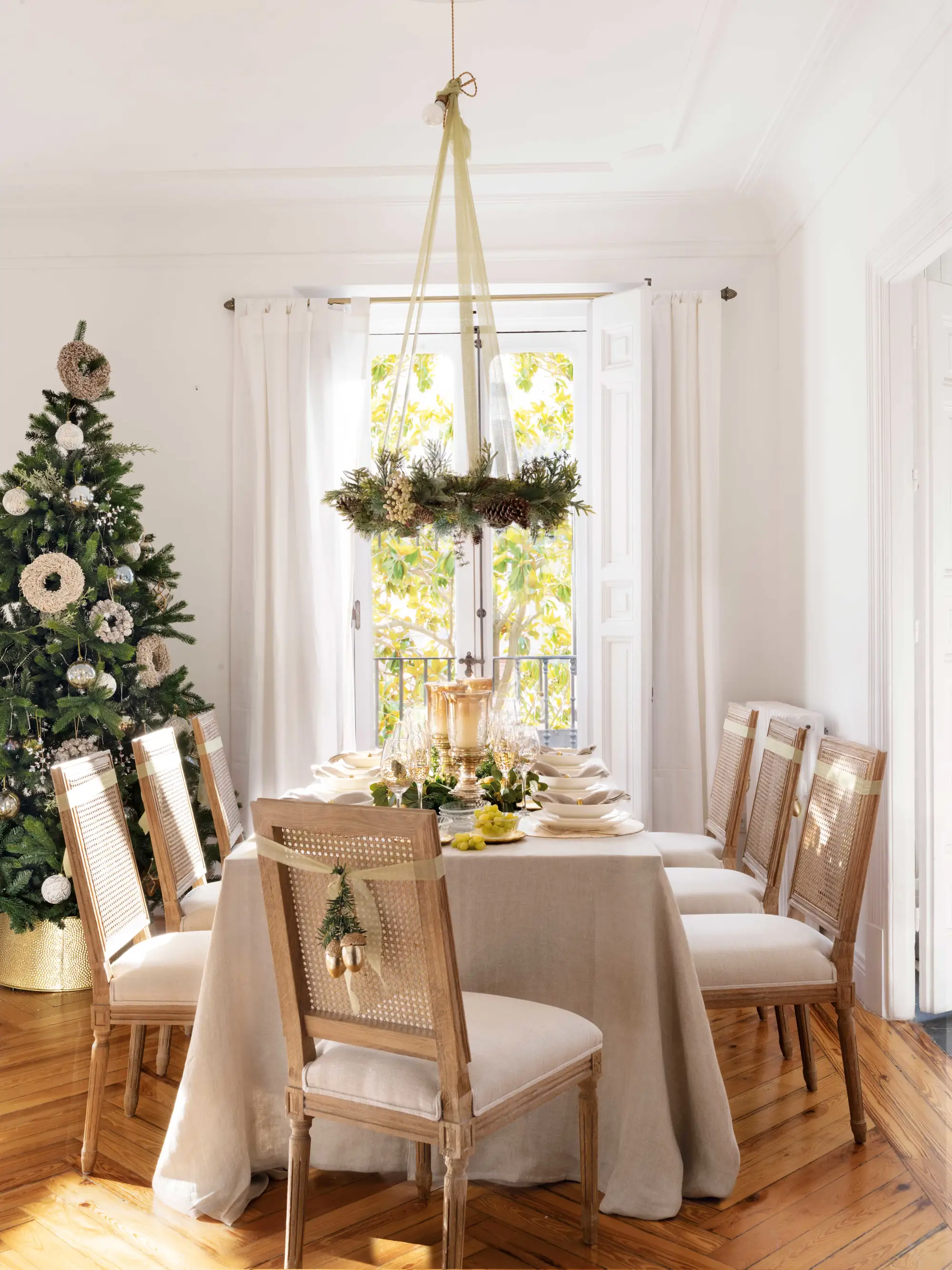 Comedor de Navidad con mesa vestida, árbol y sillas decoradas