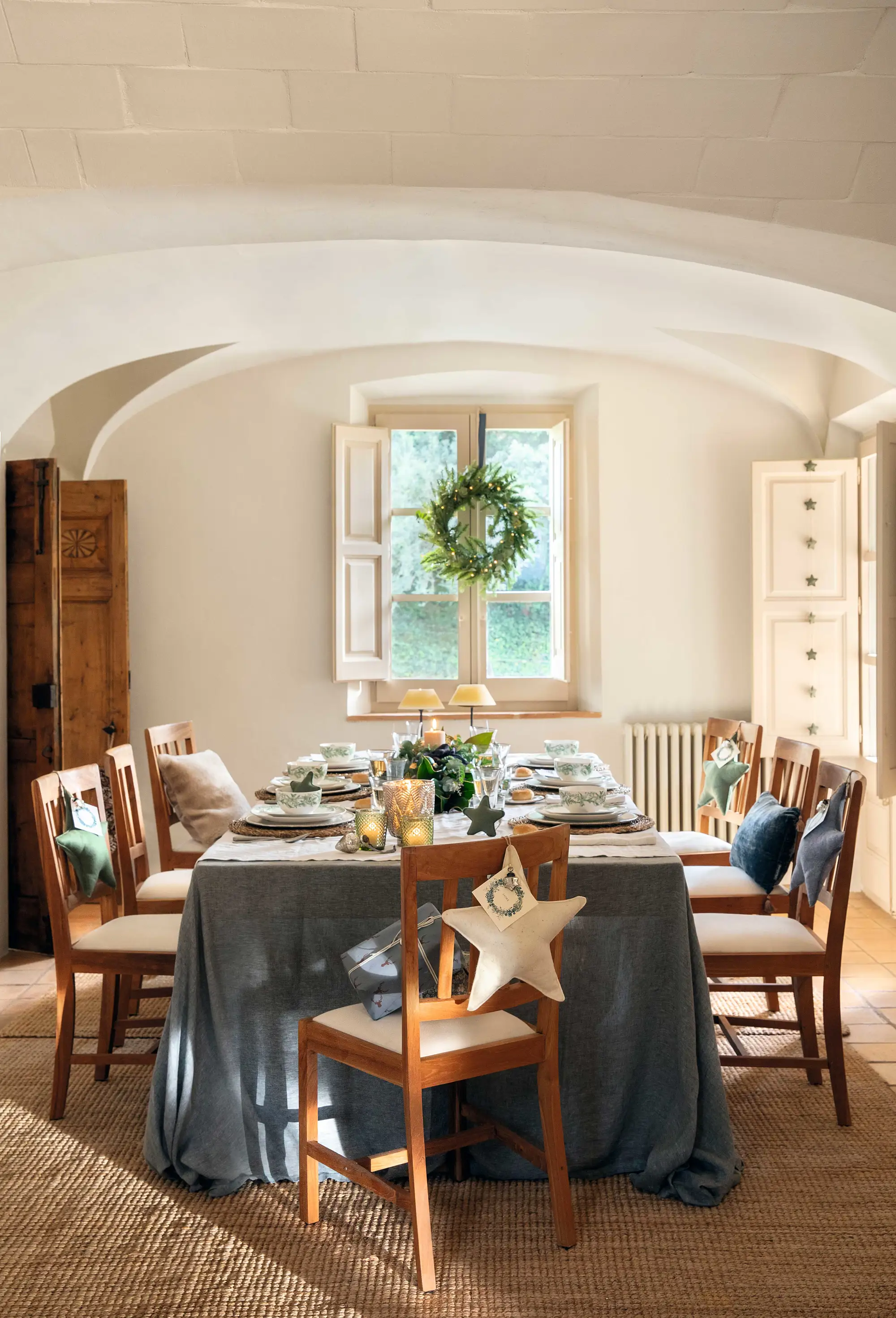 Comedor de Navidad con mesa vestida, corona en ventana y silla decorada