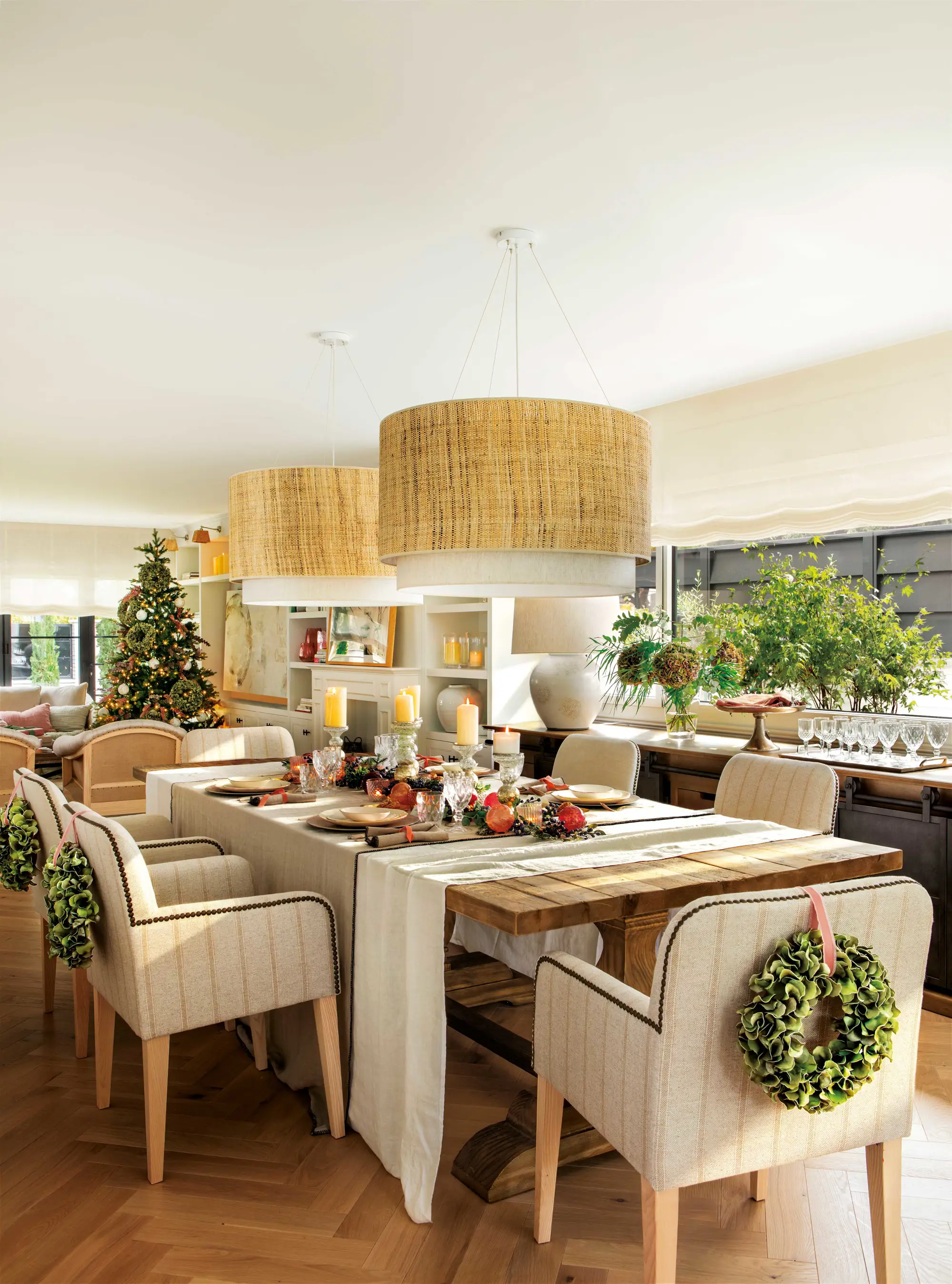 Comedor de Navidad con mesa vestida, lámparas suspendidas y sillas decoradas con coronas