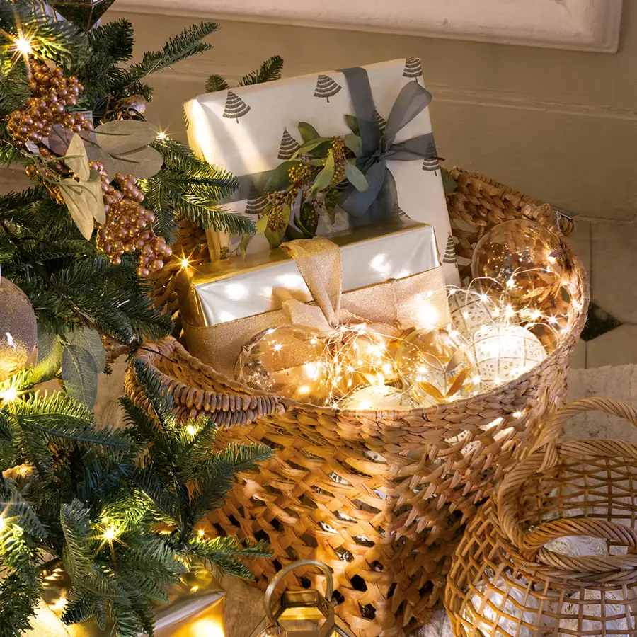 Detalle de cesto de fibras con bolas, guirnalda de luces y regalos