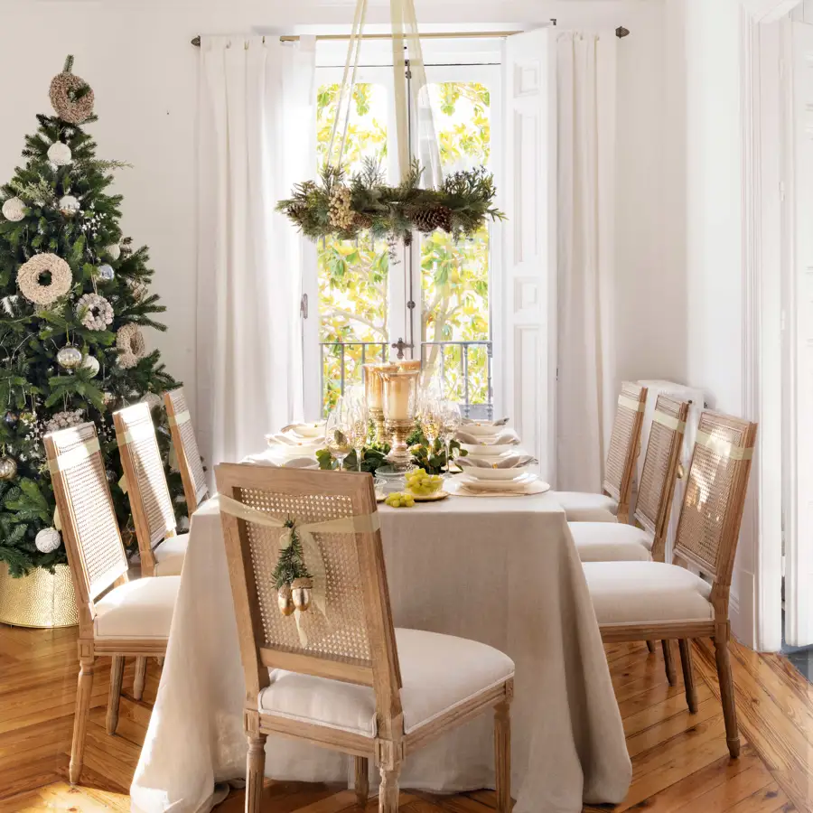 Comedor de Navidad con mesa vestida, árbol y sillas decoradas