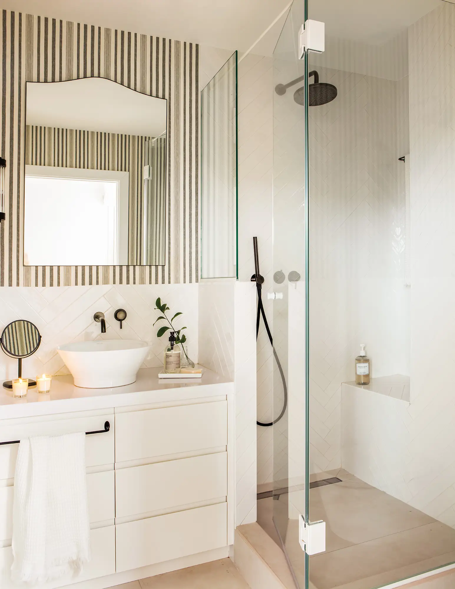 Baño pequeño con pared del lavabo decorada con un papel a rayas.