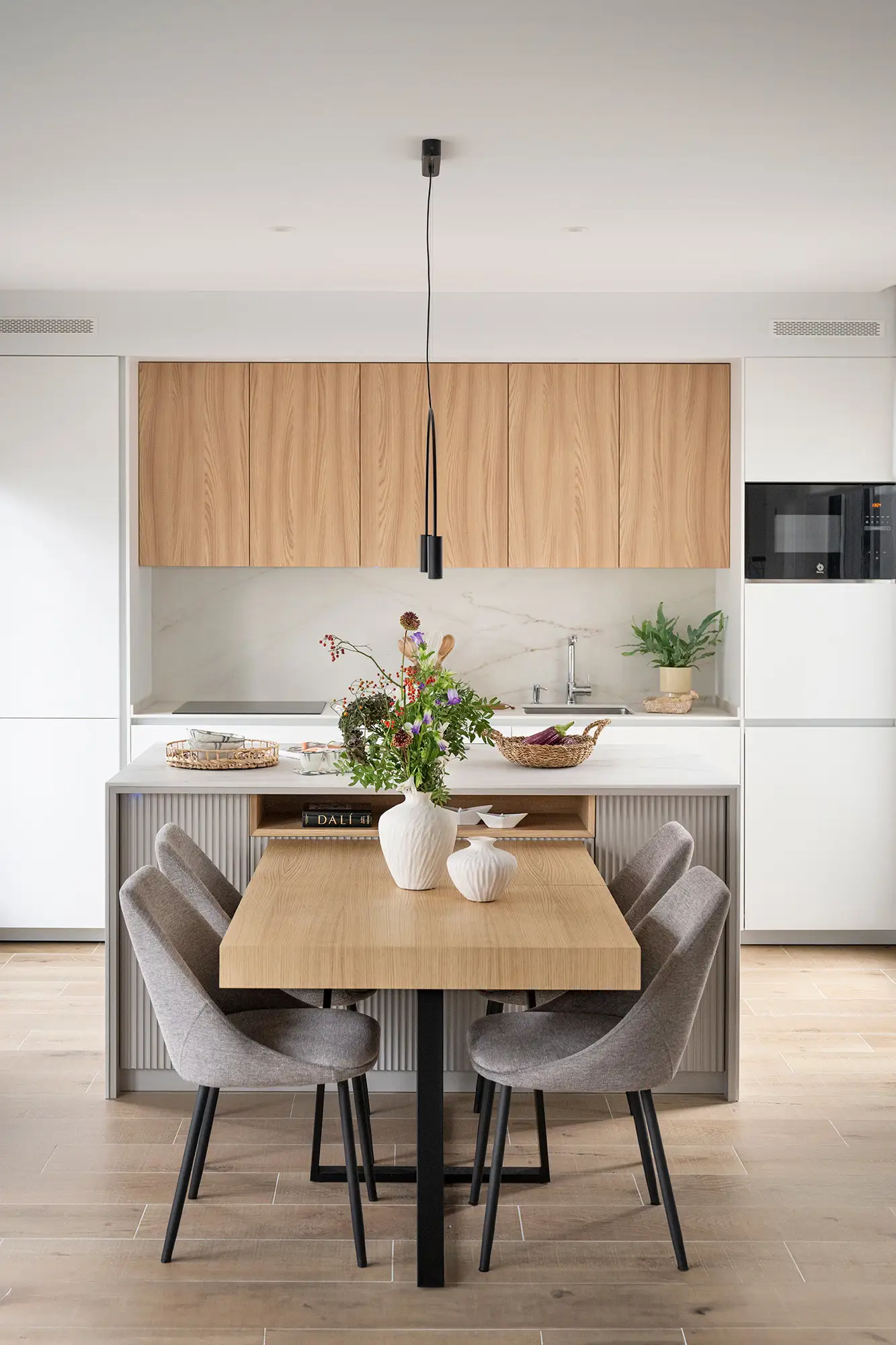 Cocina con isla y mesa de comedor adosada, diseño de Wood Estudio