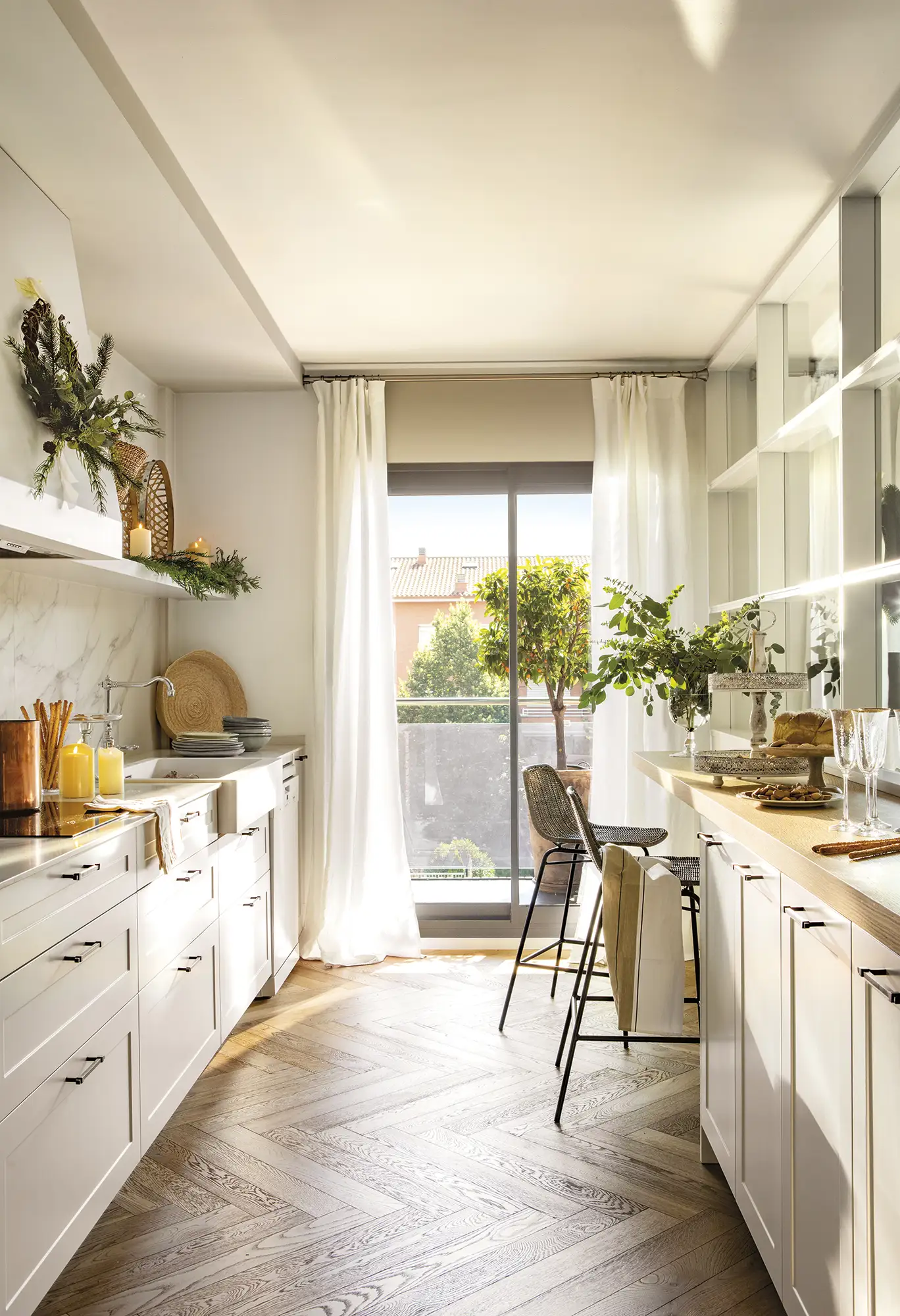 Cocina blanca con suelo de madera de espiga y barra con taburetes