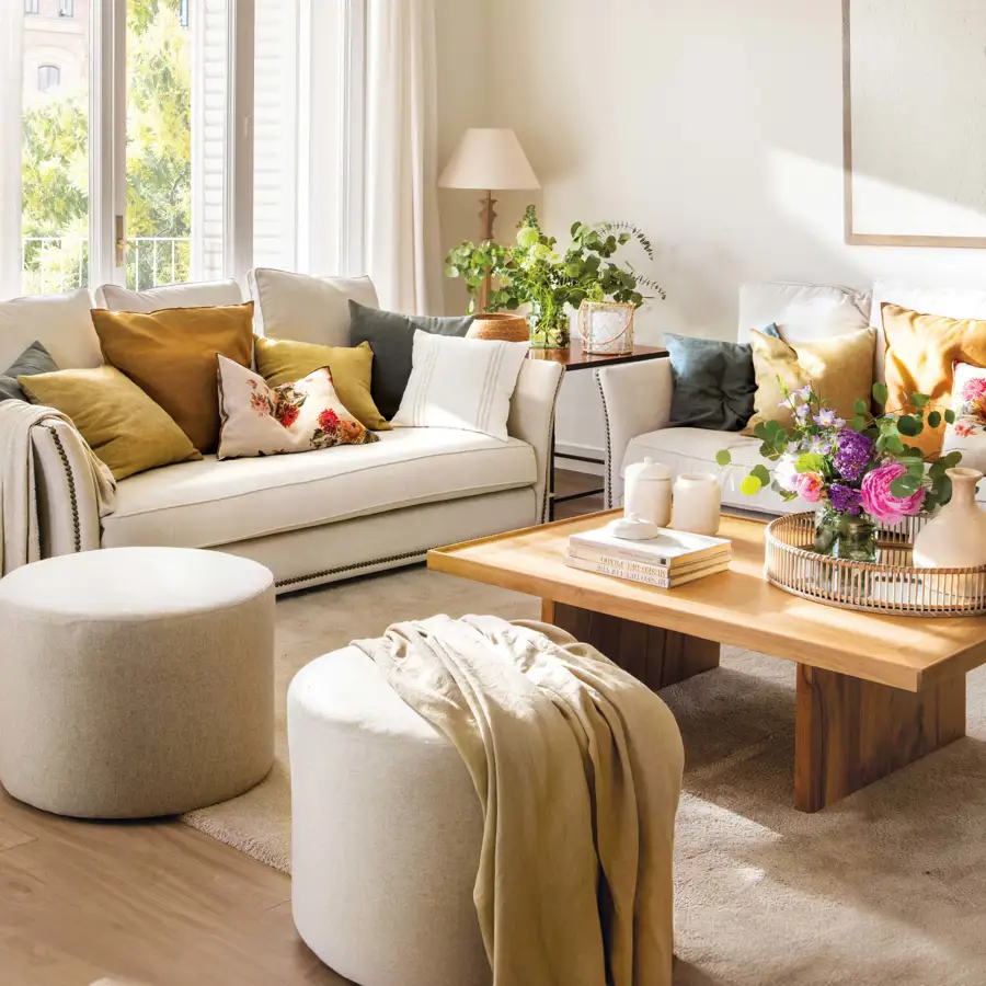 Salón pequeño con sofás en L, mesa de madera y pufs