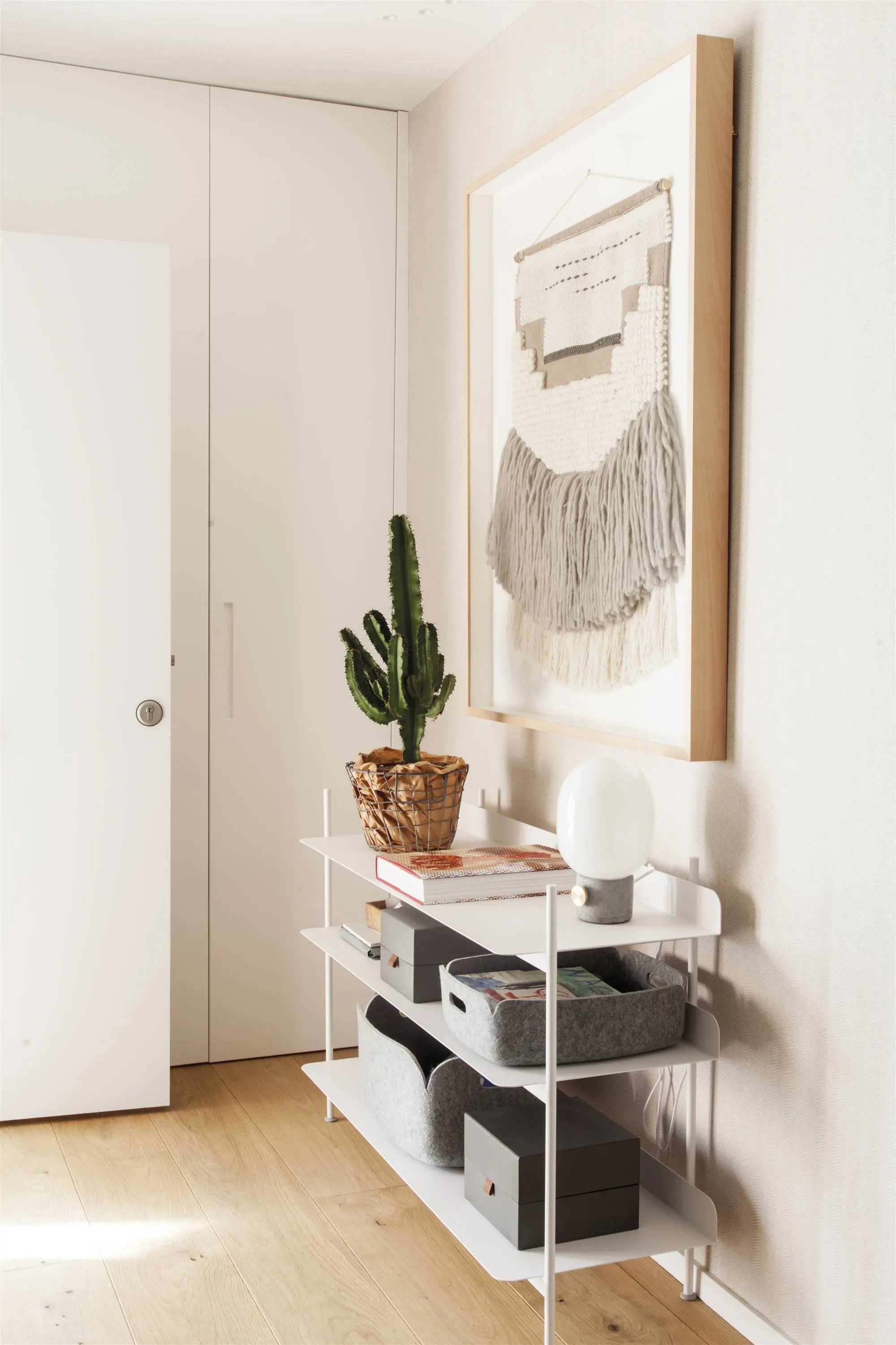 Recibidor con mueble blanco y cuadro textil.