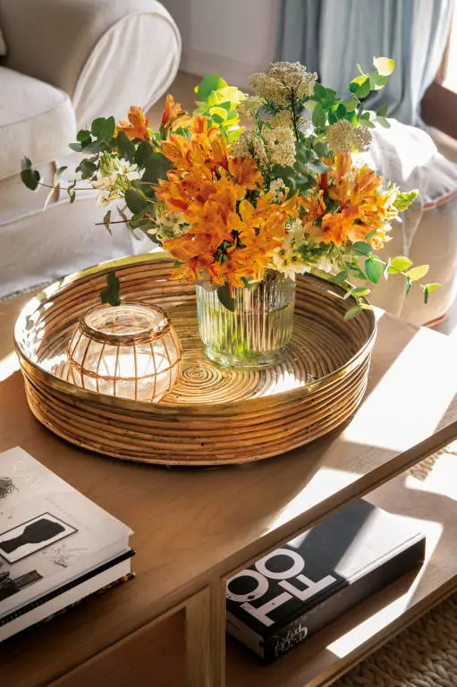 Arreglo floral en una bandeja de mimbre que decora la mesa de centro.