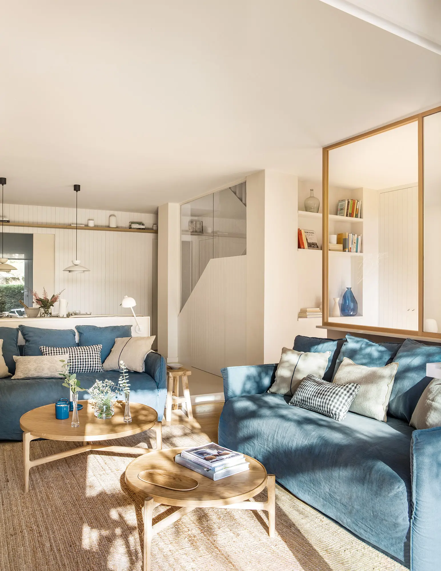 Salón con sofá azul apoyado en cerramiento.