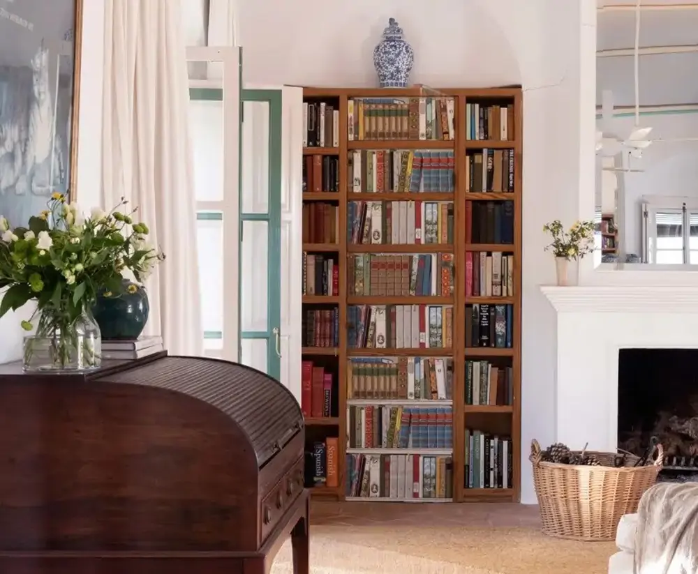 Detalle de Salón con chimenea, secreter y puerta que parece una librería, trampantojo