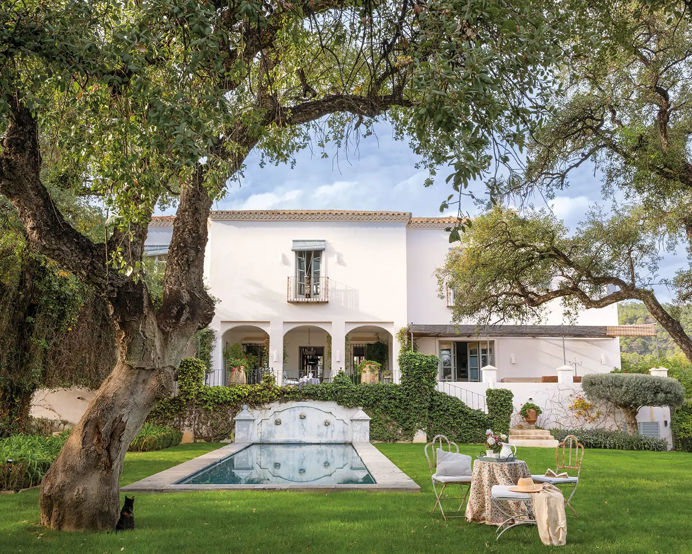 Casa con fachada con arcos y jardín con alberca y tres caños