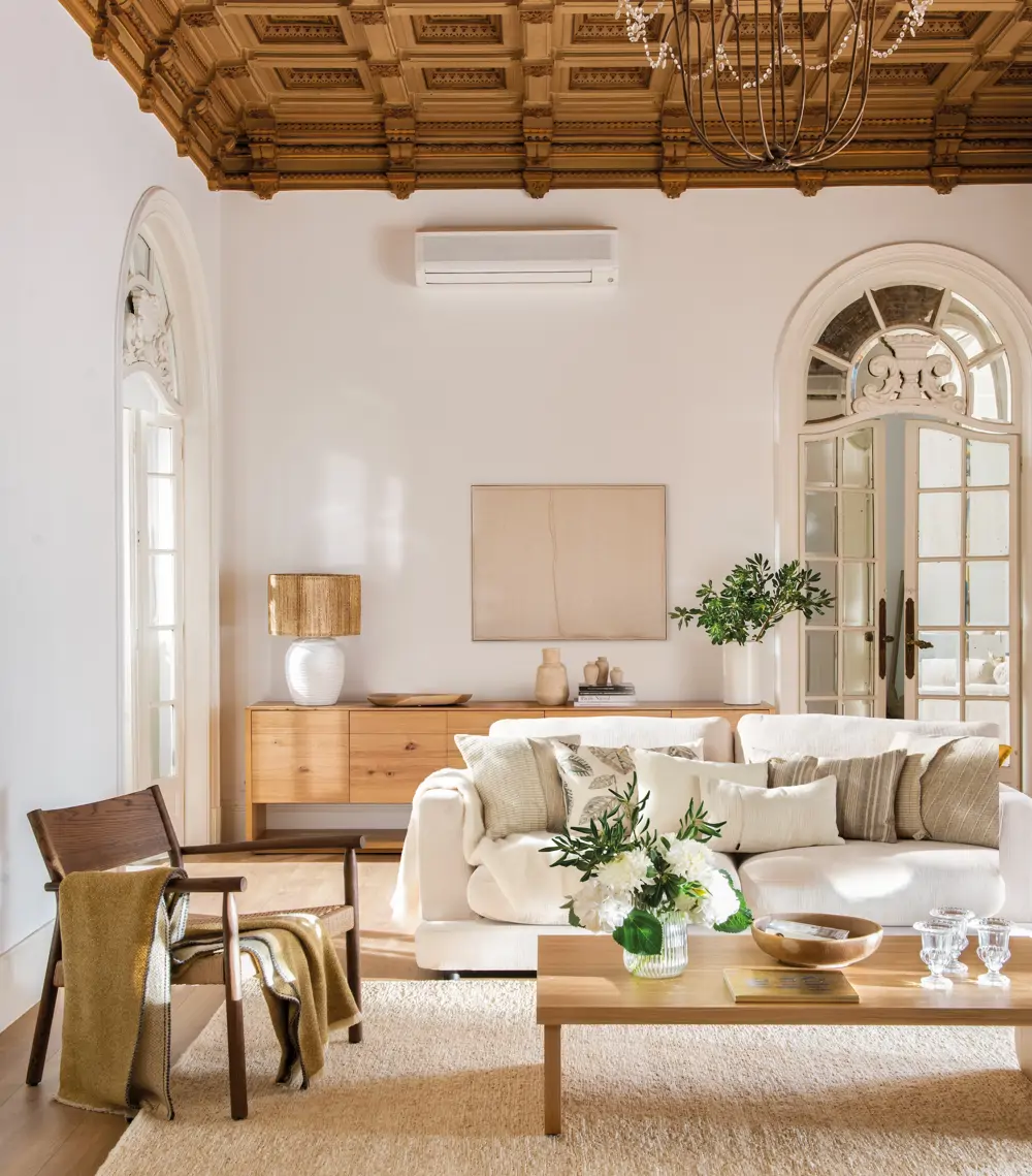 Salón con sofá blanco, mesa de centro, butaca y aparador de madera