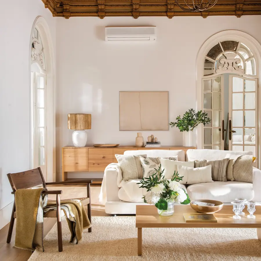 Salón con sofá blanco, mesa de centro, butaca y aparador de madera