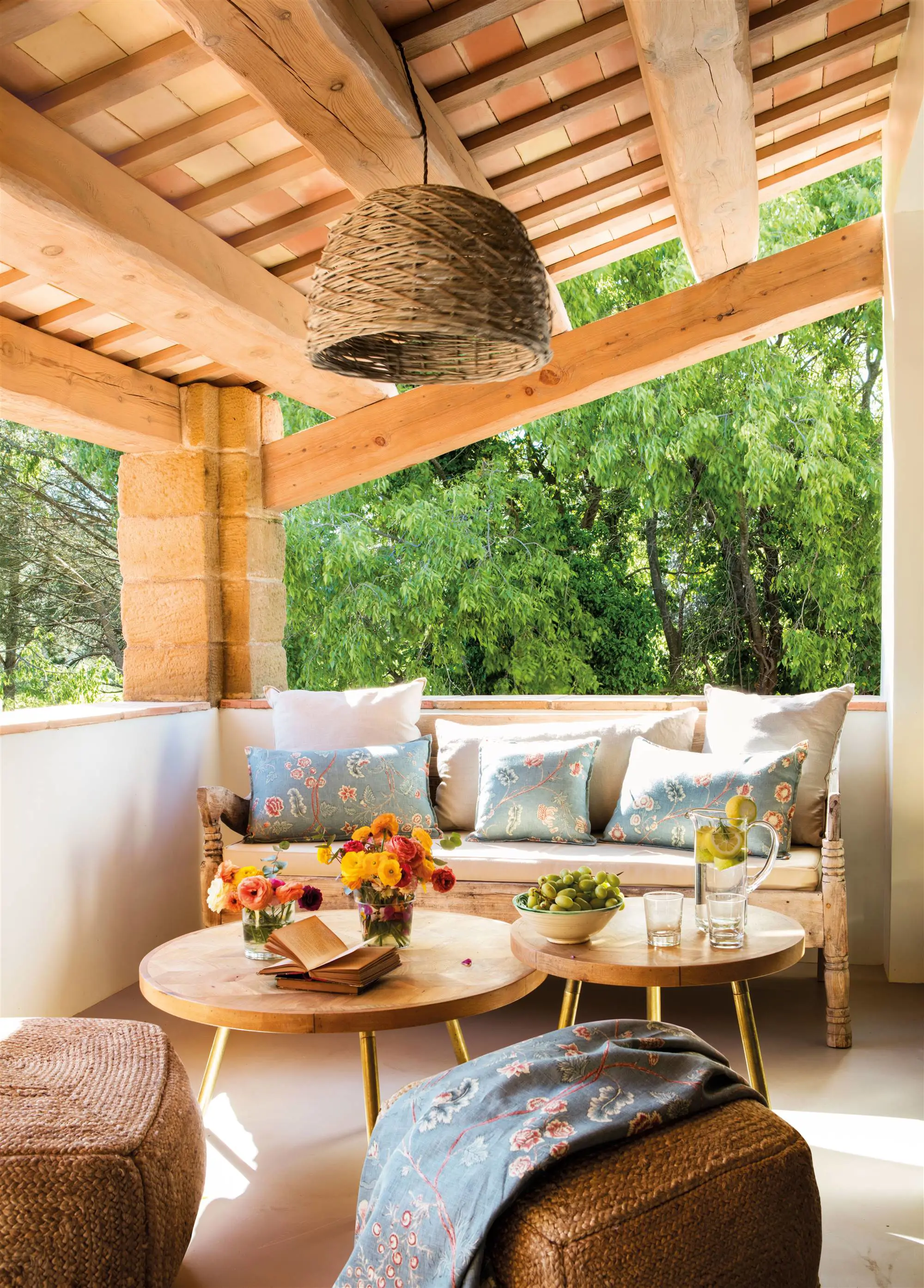 Terraza bajo un porche con muebles de madera y fibras vegetales.