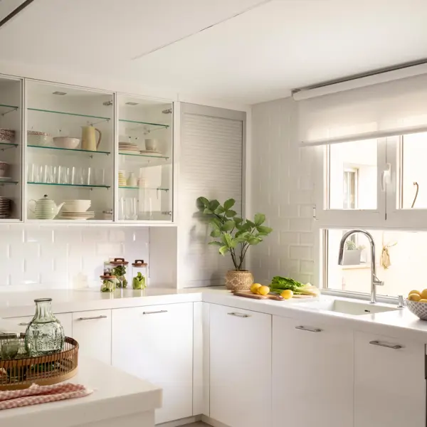 Cocina blanca con mueble con puerta de persiana que oculta la cafetera