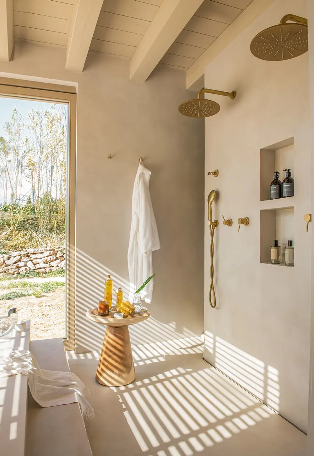 baño sin mampara ducha dorada ventana natural microcemento