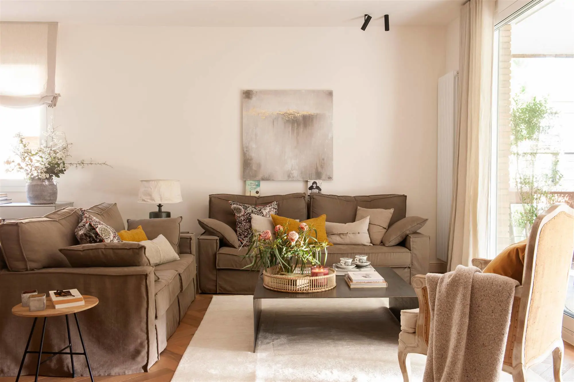 Salón atemporal con sofás enfundados con tela marrón, butaca recuperada y mesa de centro de diseño