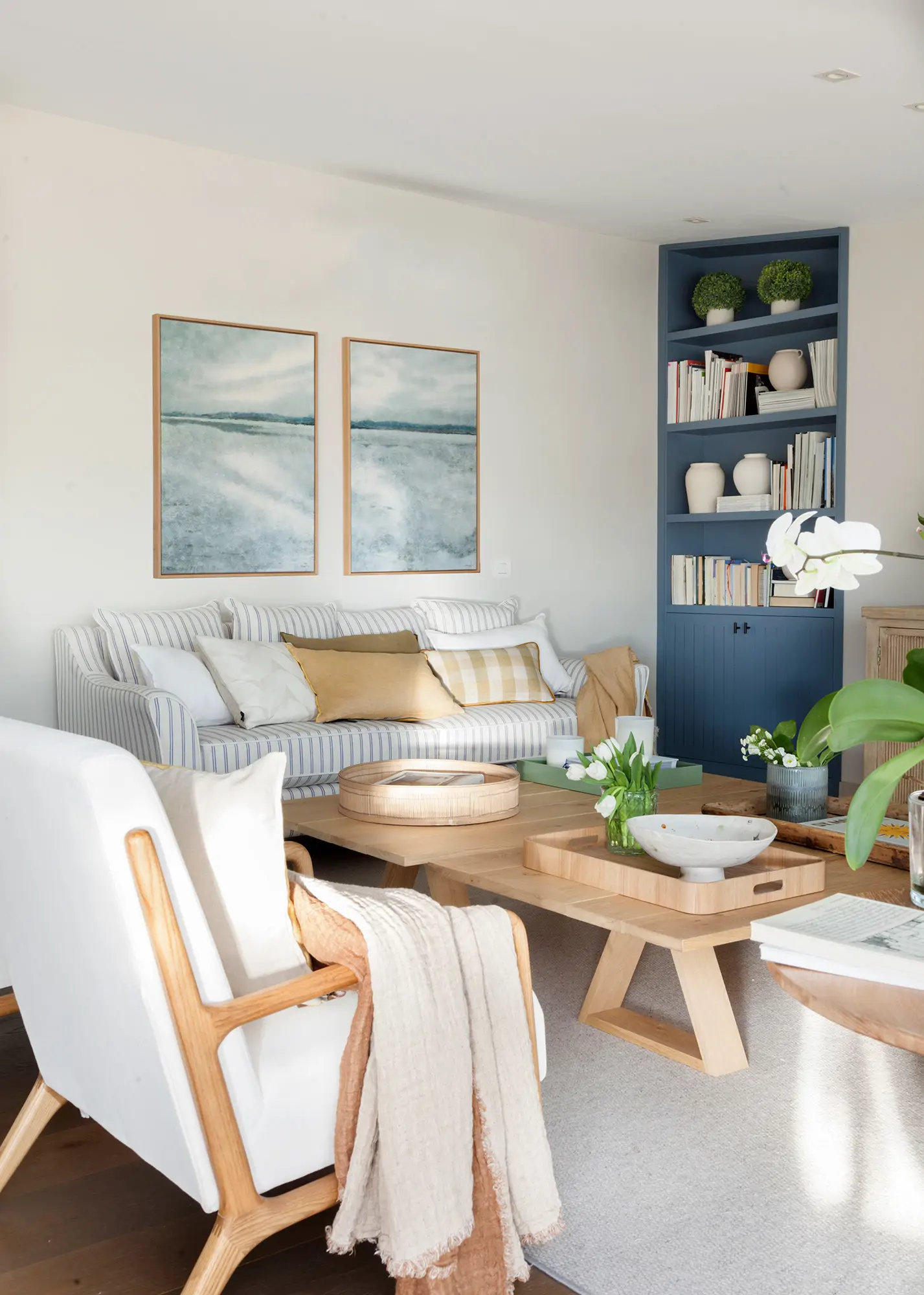 Salón pequeño y moderno con estantería pintada de azul y sofá con rayas marineras
