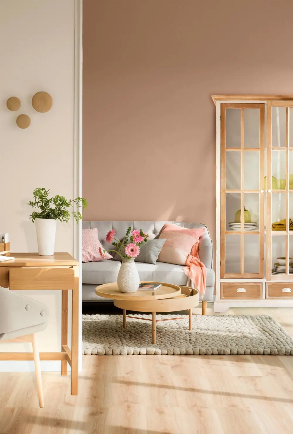 salon con pared rosa y sofa gris con mesa de centro consola y armario en madera clara
