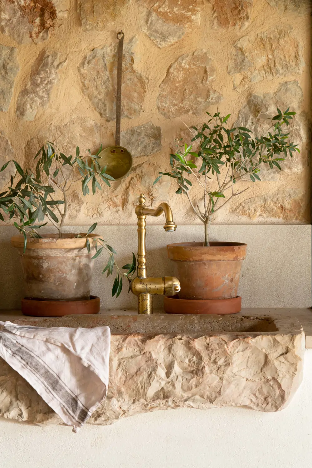Detalle de grifo dorado en cocina con pared de piedra