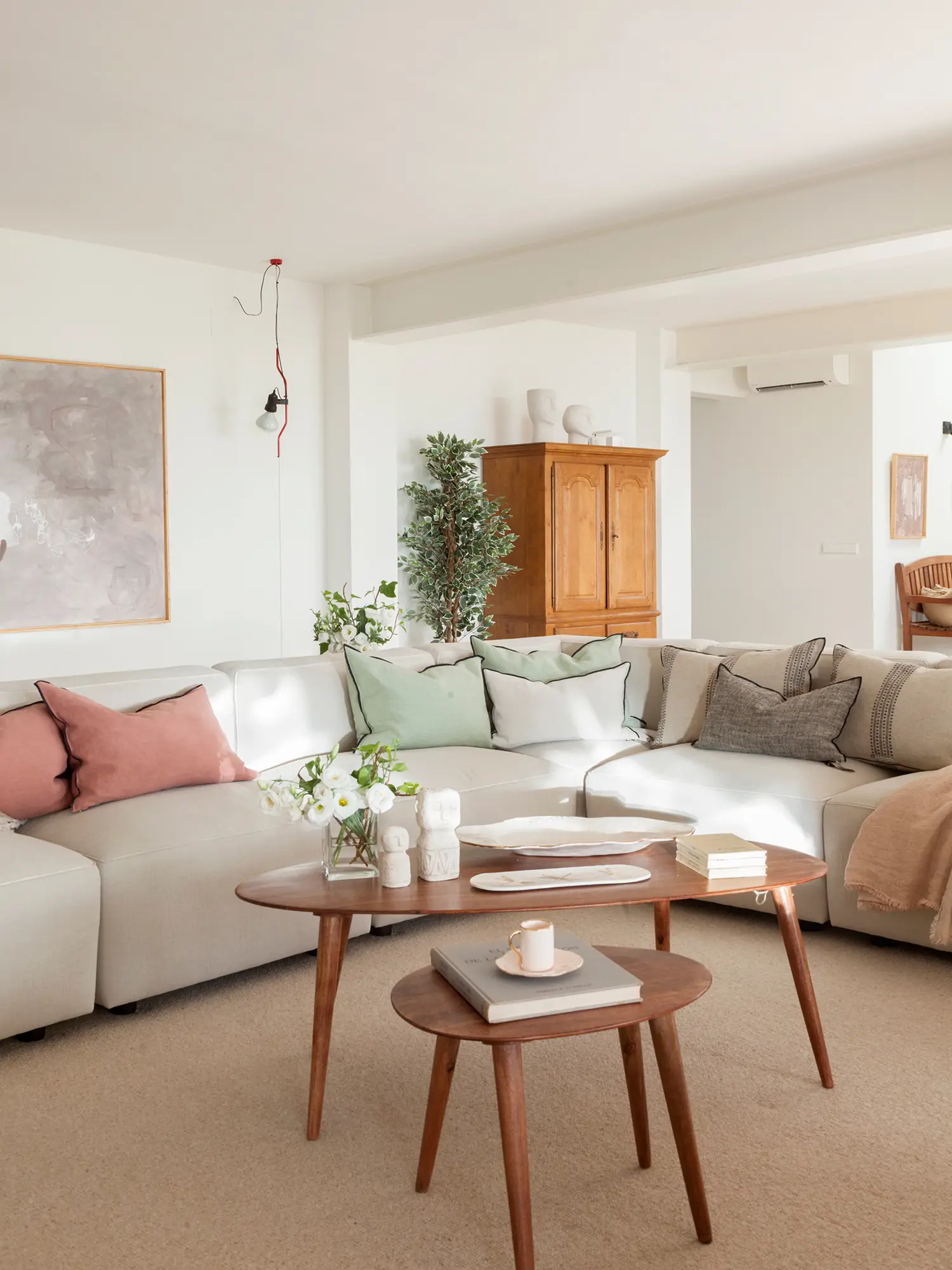 Salón moderno con sofá en L y mesas nido de madera.