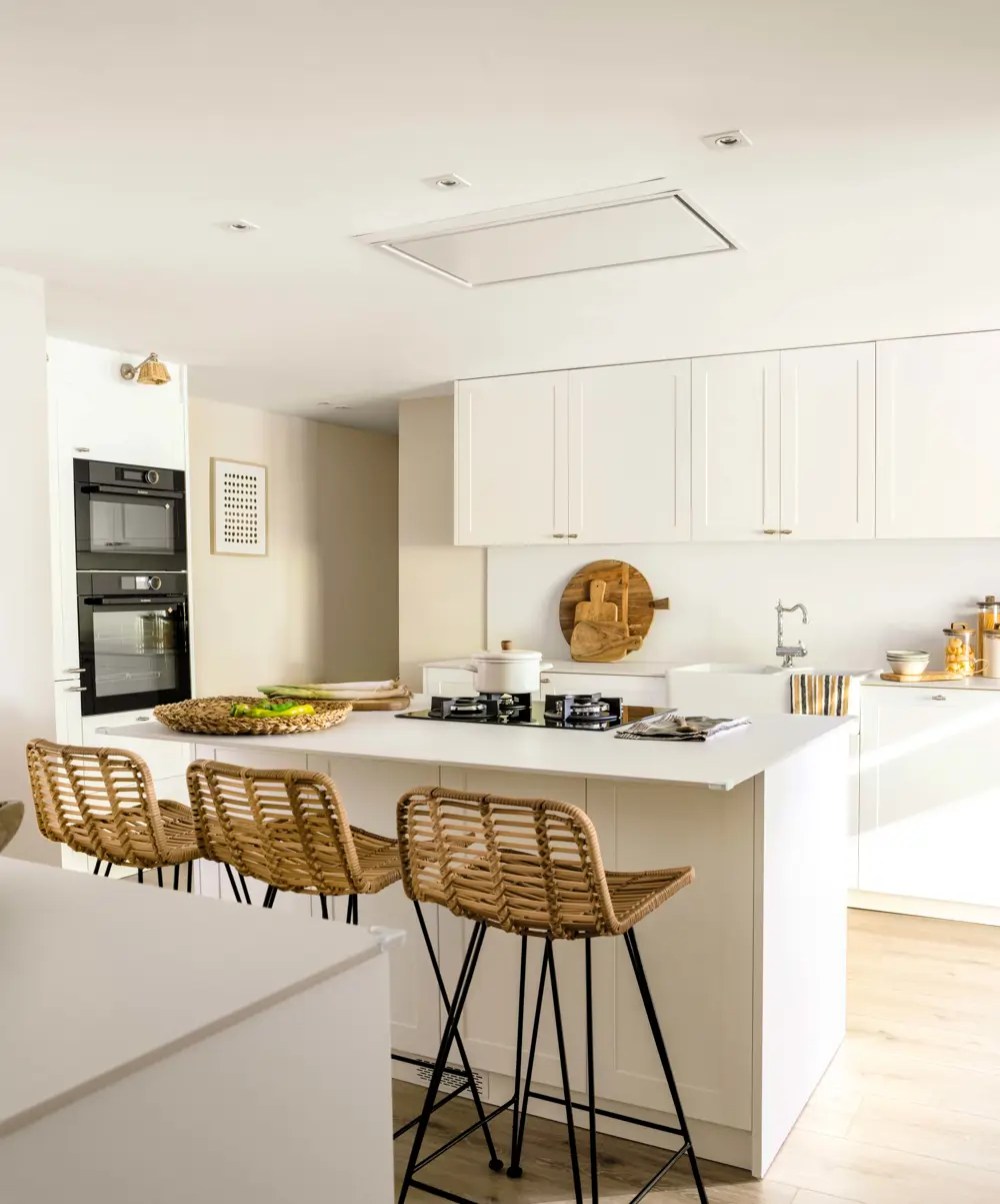 Cocina blanca con isla, taburetes de fibra y hornos en columna
