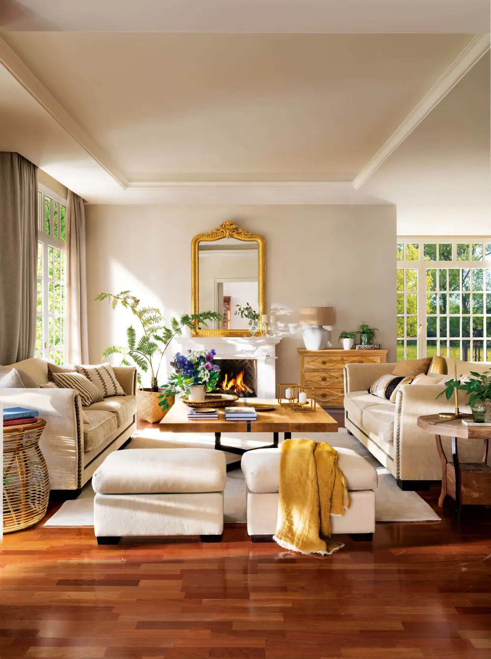 Salón con sofás blancos, espejo dorado y suelo de madera oscuro