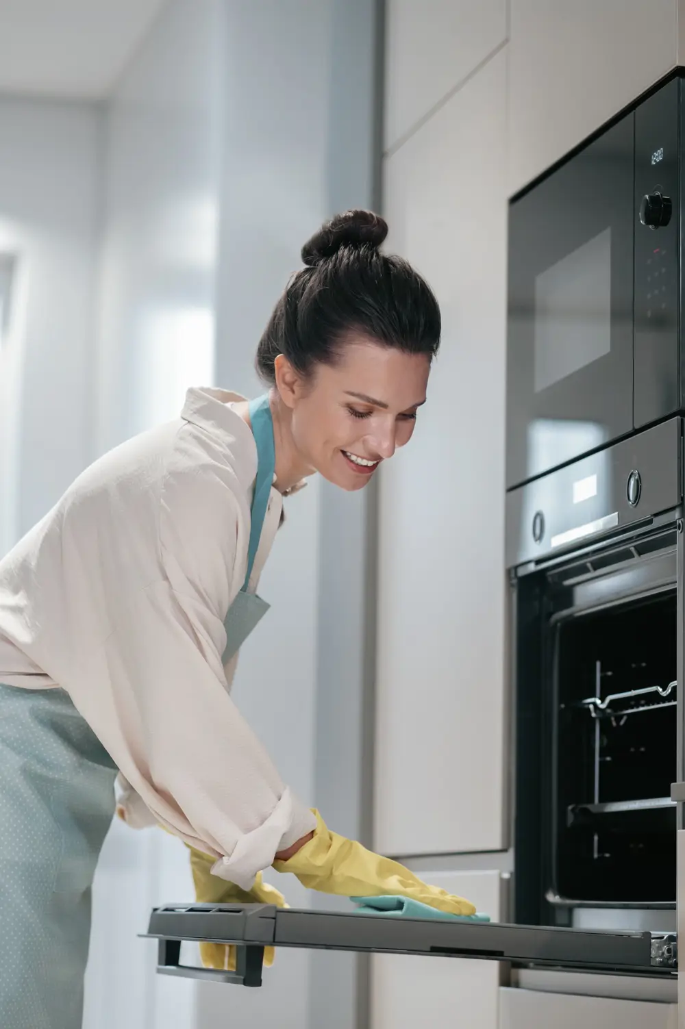 Mujer limpiando el horno de su casa de forma fácil.
