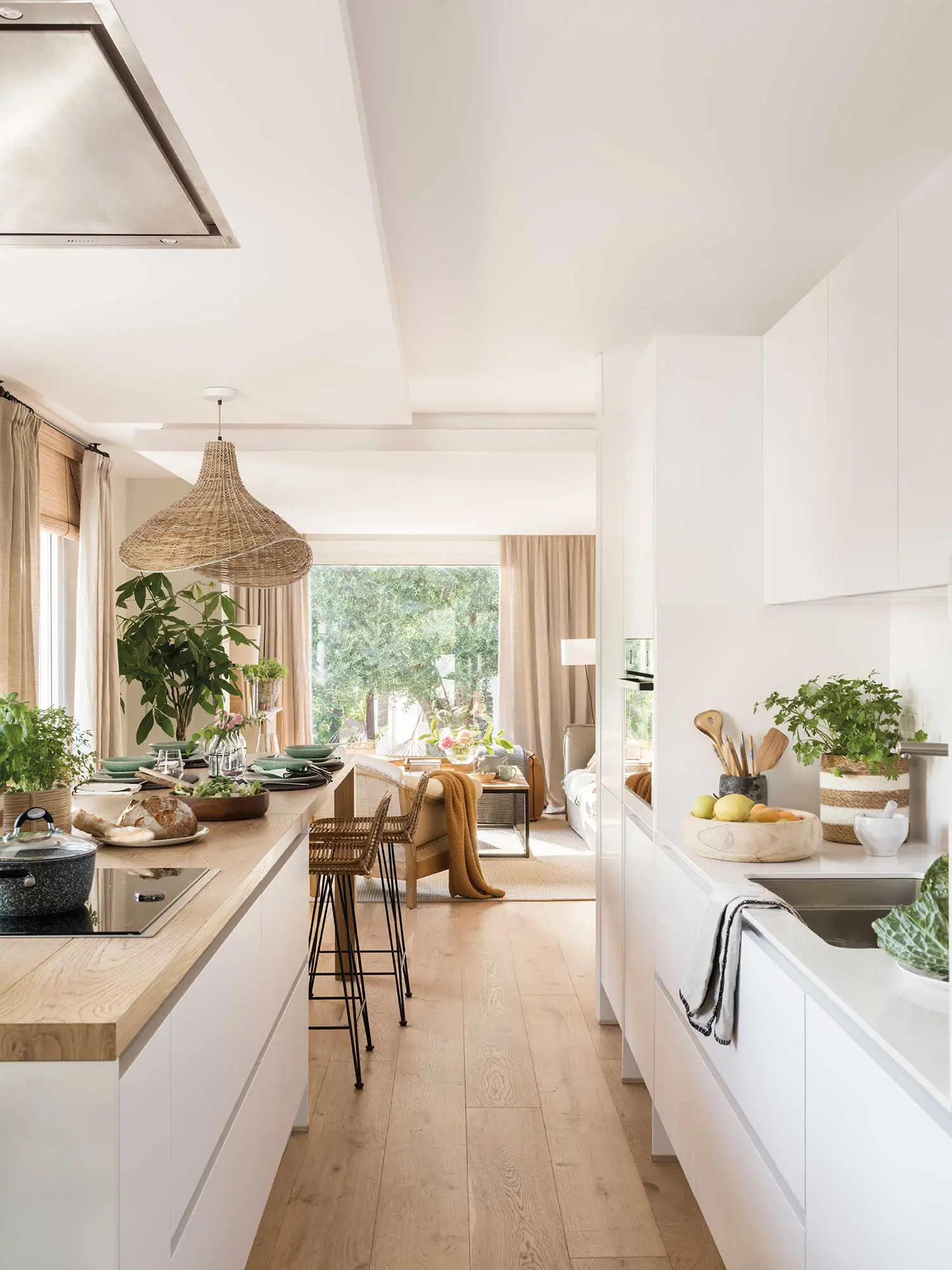 Cocina blanca abierta al salón con suelo de madera