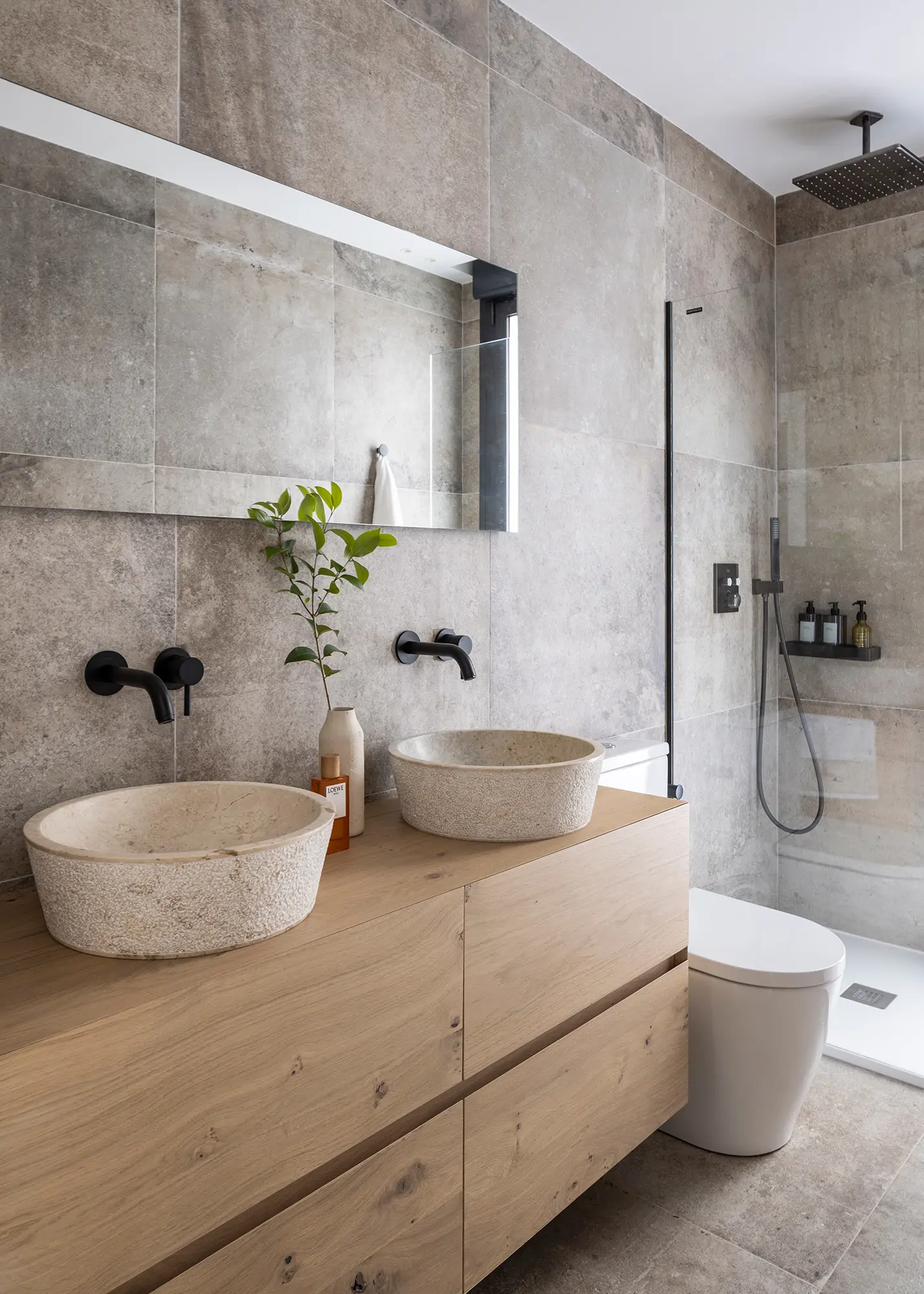 Baño con mueble de madera y lavamanos de piedra.
