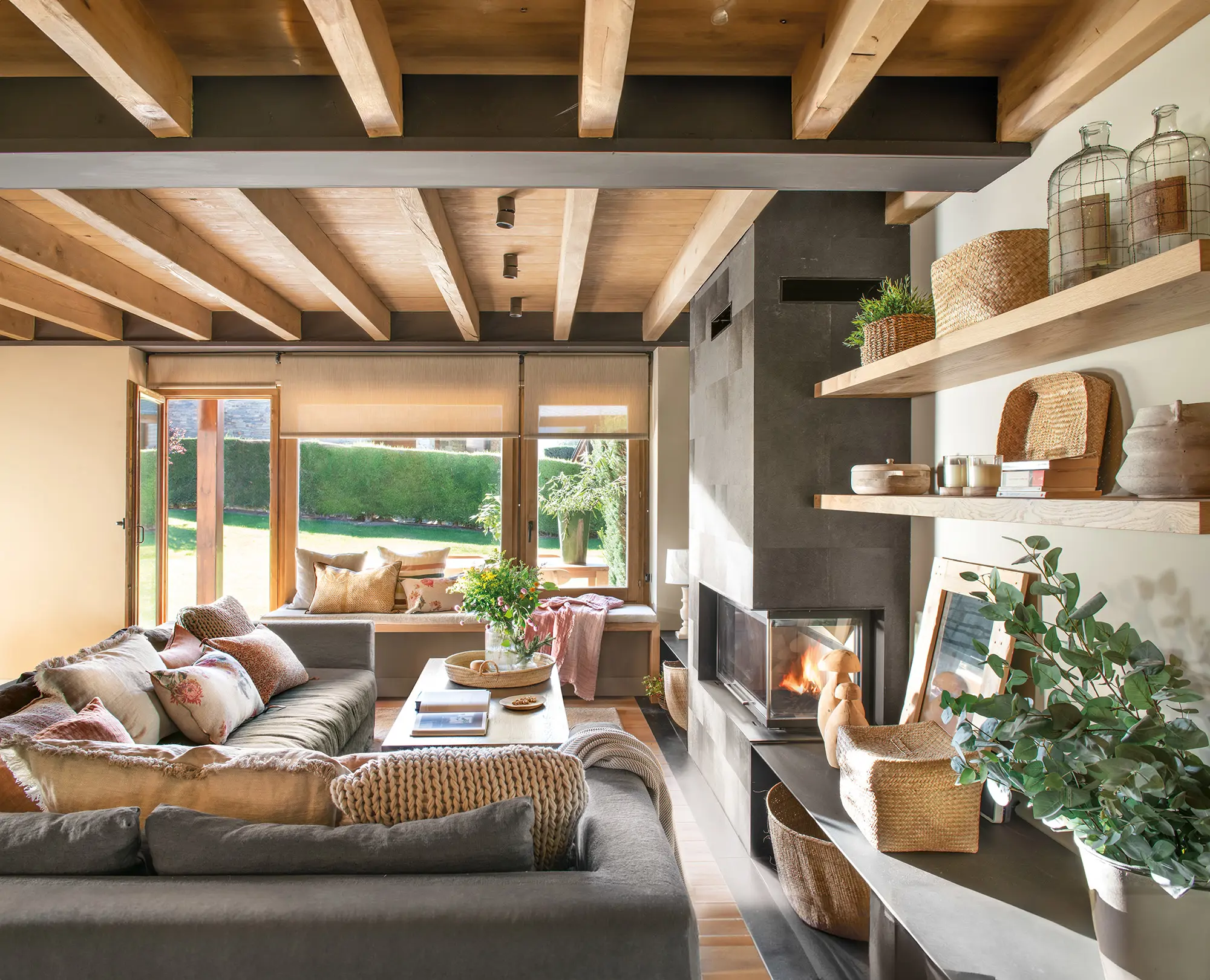Salón con sofá rinconero y techo de madera.