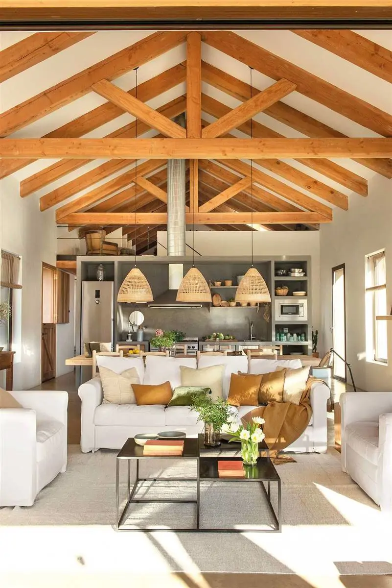 Salón con cocina integrada y vigas de madera en el techo.