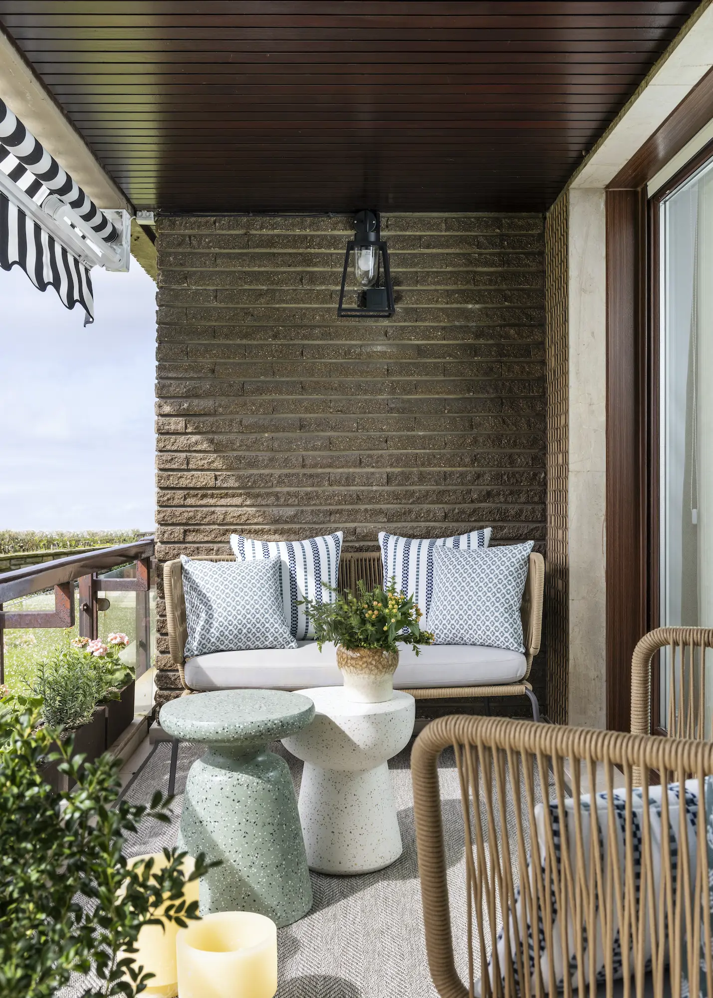 Terraza decorada con muebles de fibra y mesitas auxilires.