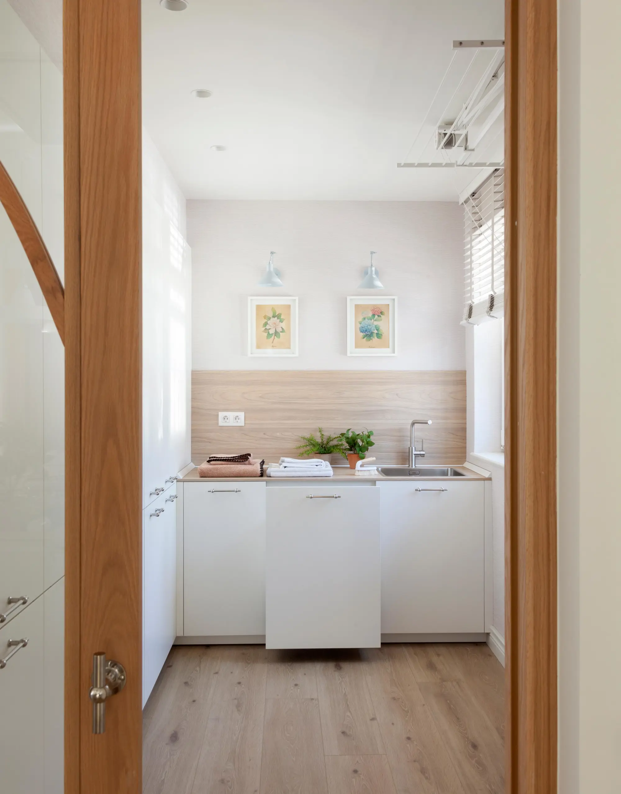 Lavadero con mobiliario blanco y suelo porcelánico acabado madera