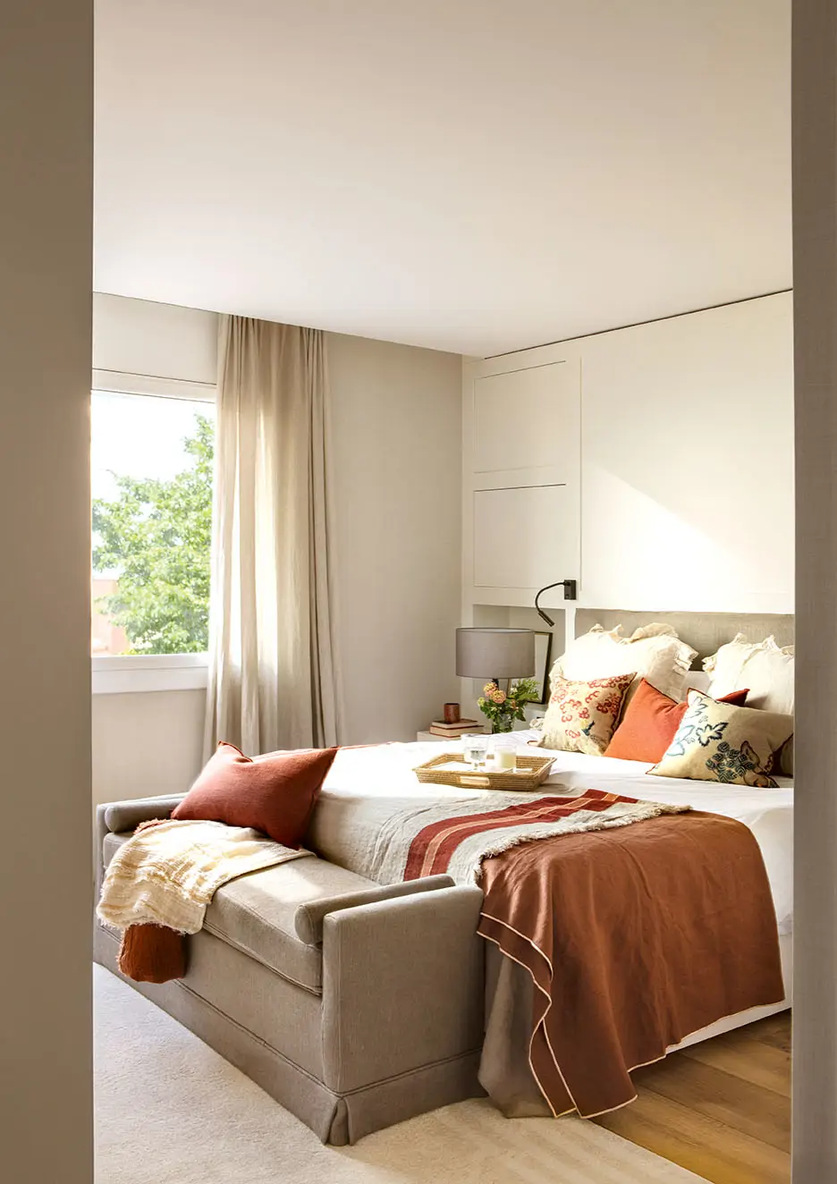 Dormitorio con cabecero plafonado, banco tapizado y ropa de cama en gris y magenta