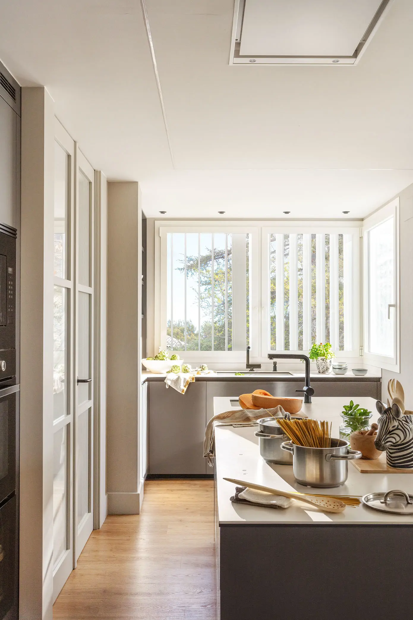Cocina gris con isla, ventana y estores