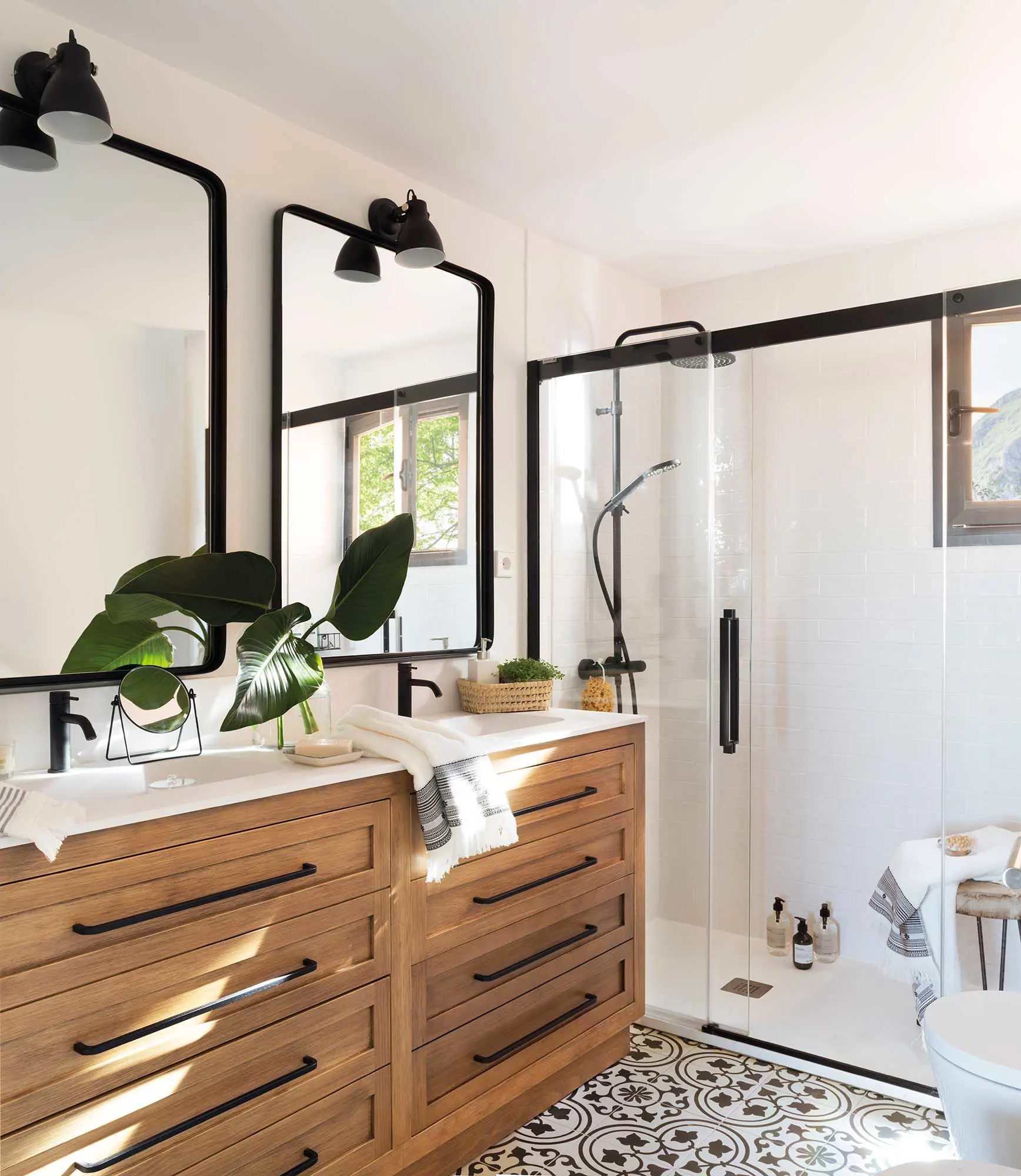 Baño con mueble de madera y mampara con perfilería negra.
