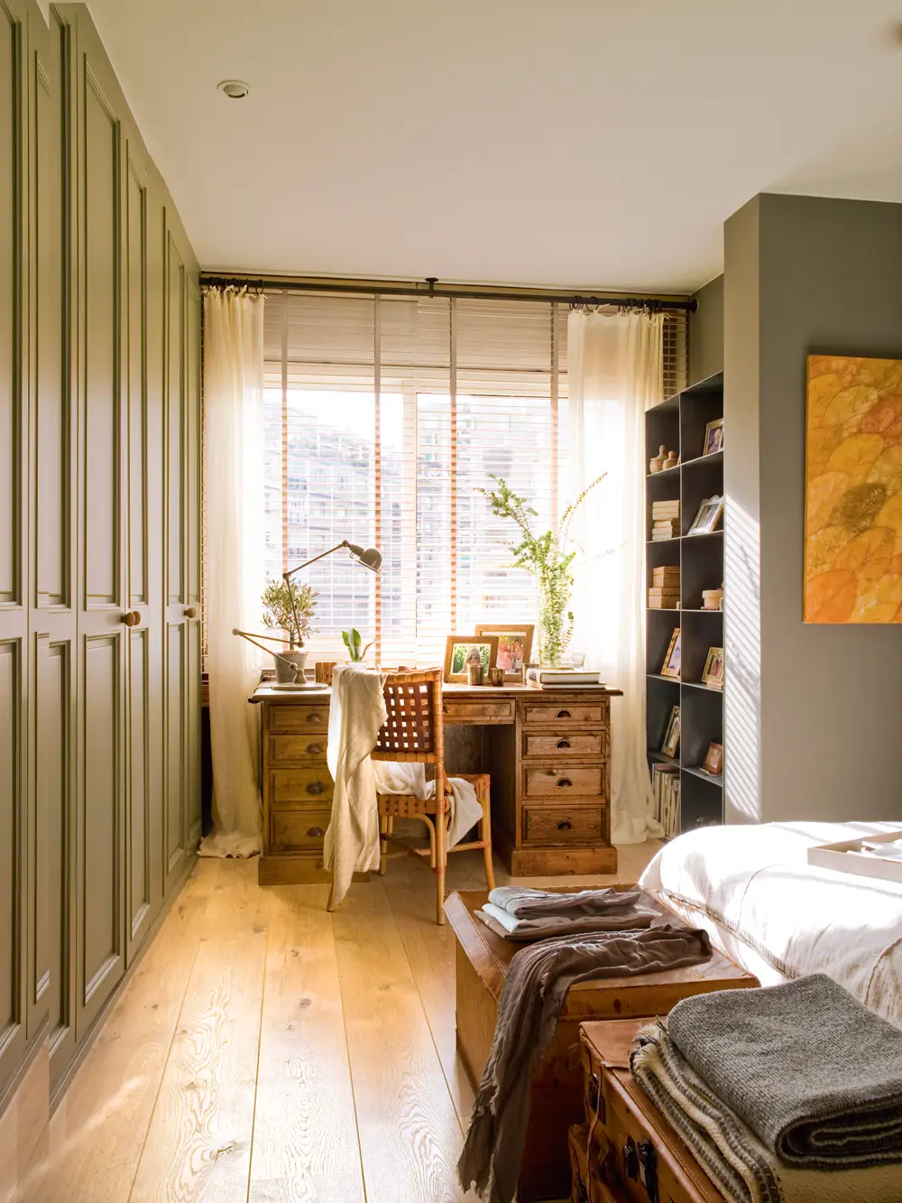 Escritorio antiguo con flexo y silla de fibras. Frente a ventana con cortinas y persiana y librería a medida 00397863