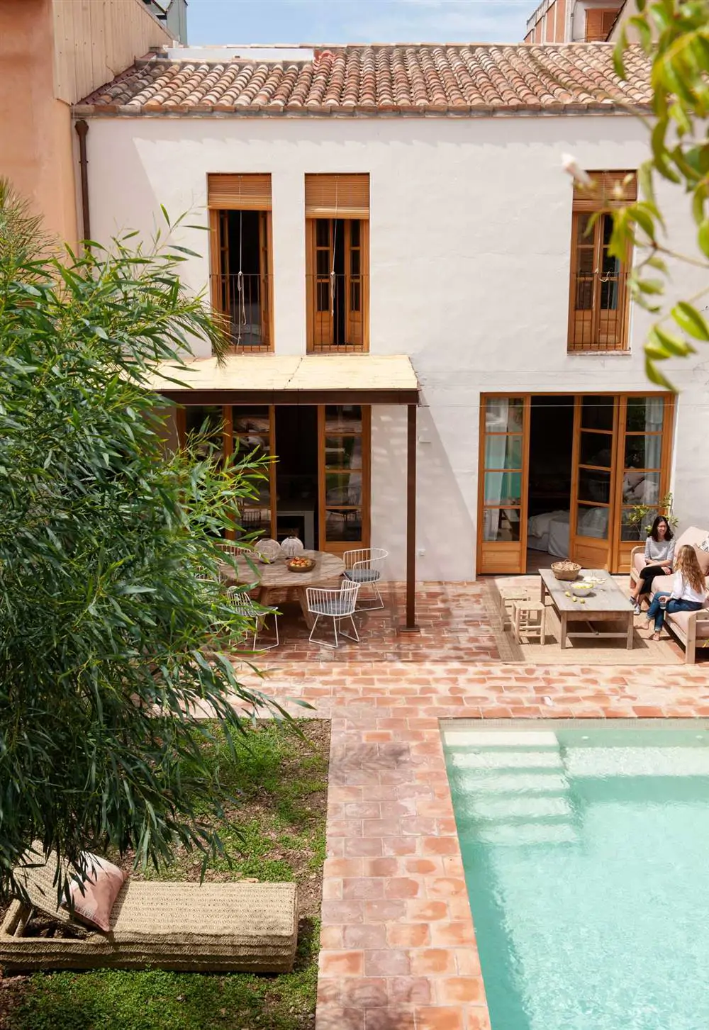 Un patio con zona de jardín y piscina de grandes dimensiones