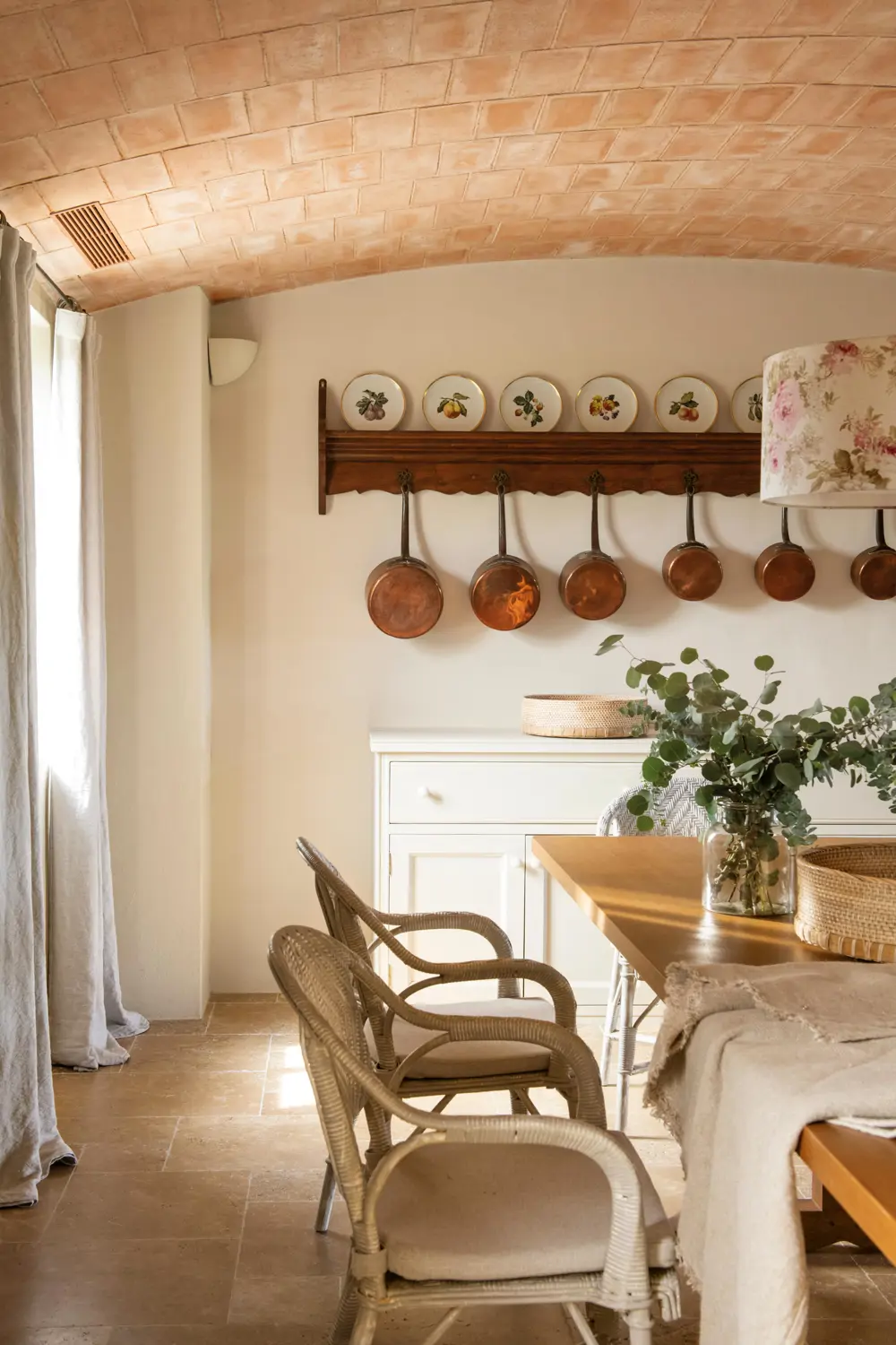 Cocina con office y pared decorada con platos de cerámica y cazos de cobre