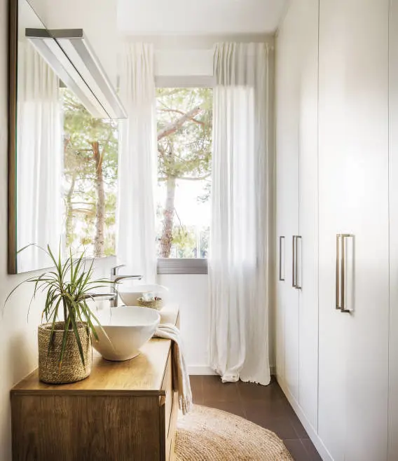 Ventana vestida con cortinas blancas hasta el suelo.