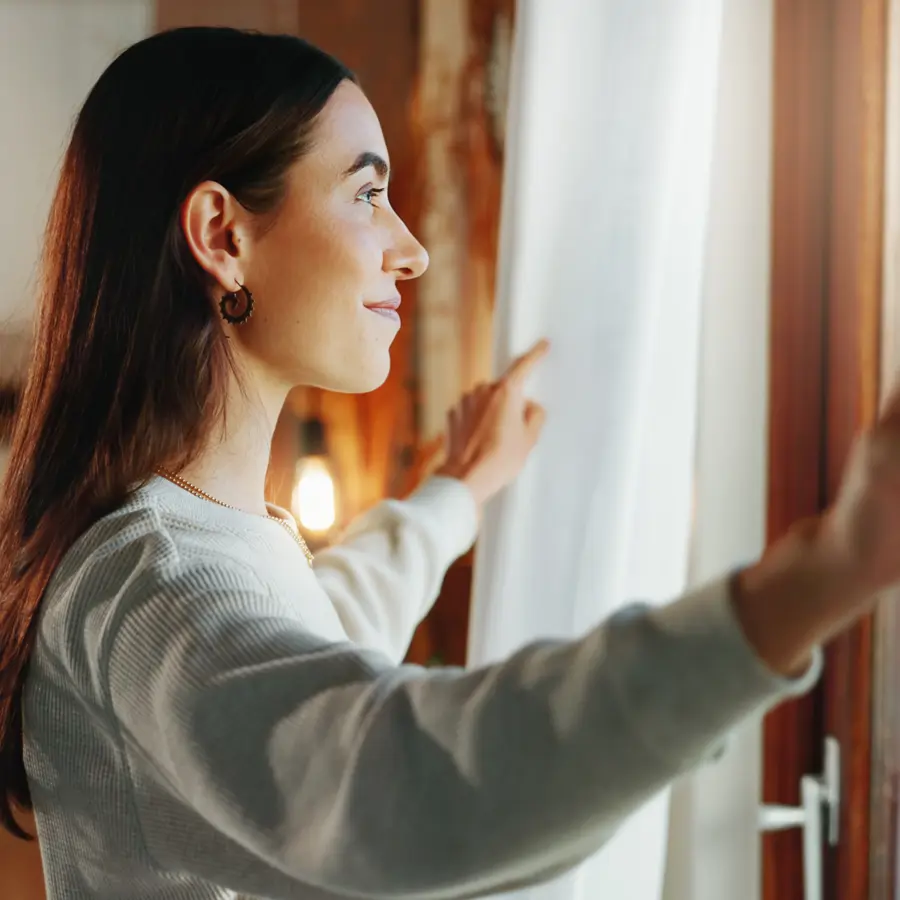 Mujer junto a ventana mosquitera iStock