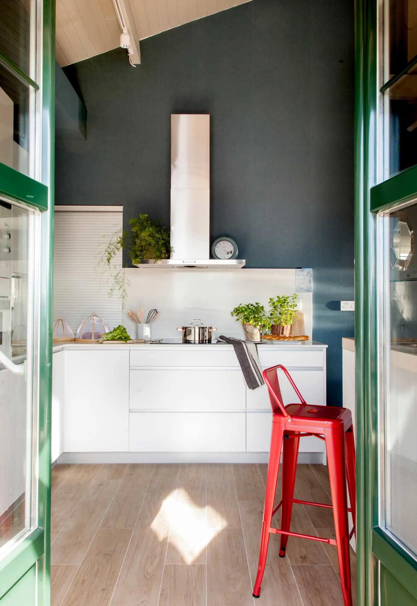 Cocina con muebles blancos y paredes de color verde oscuro.