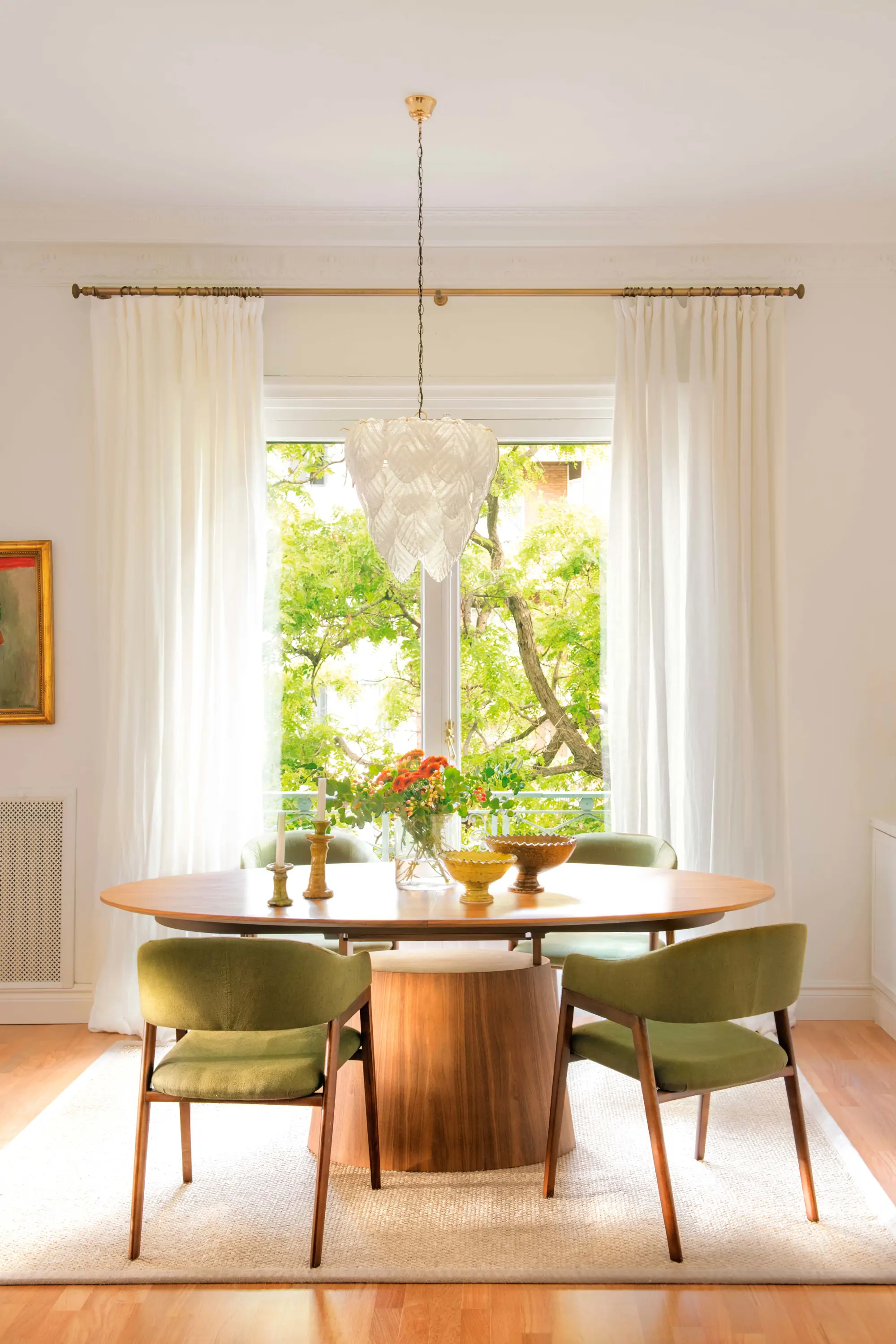 Comedor con mesa de madera redonda y sillas tapizadas en verde
