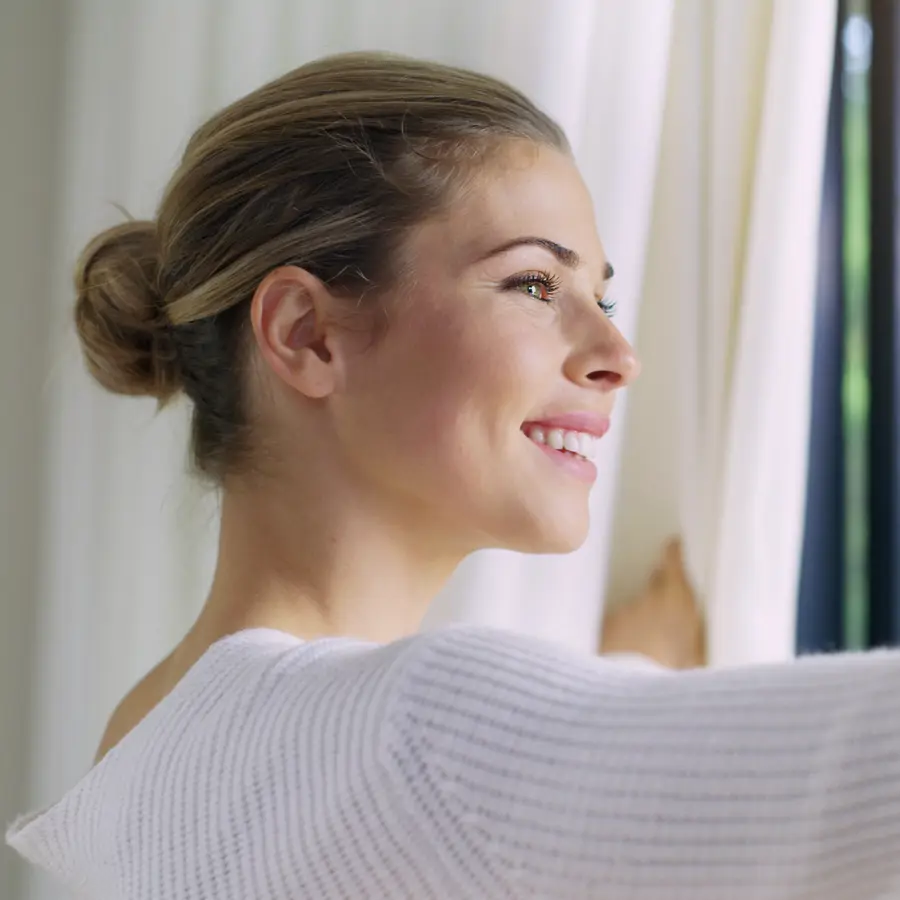 Mujer junto a la ventana con mosquitera iStock