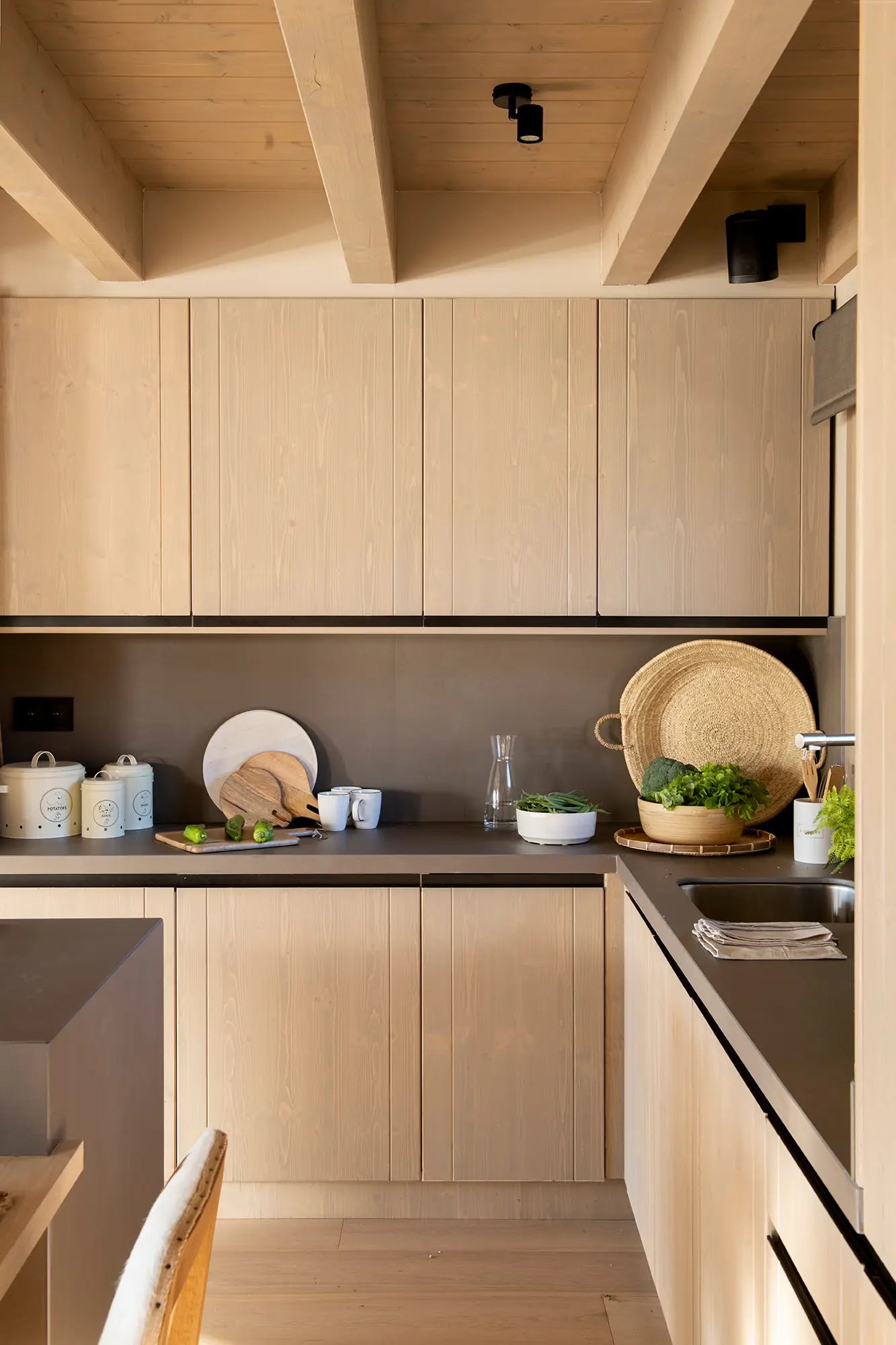 Cocina con muebles de madera y encimera en gris oscuro.