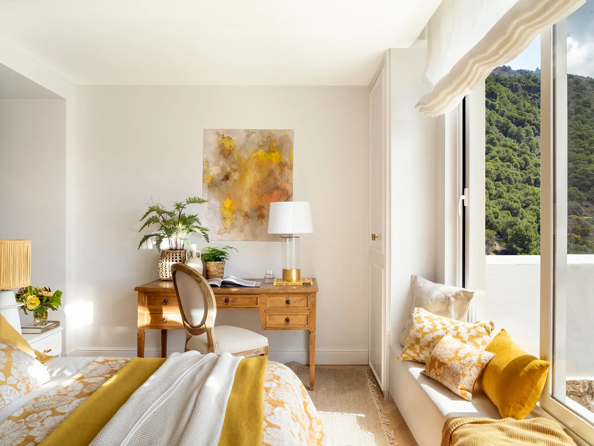 Dormitorio con cama, escritorio y banco mirador bajo la ventana